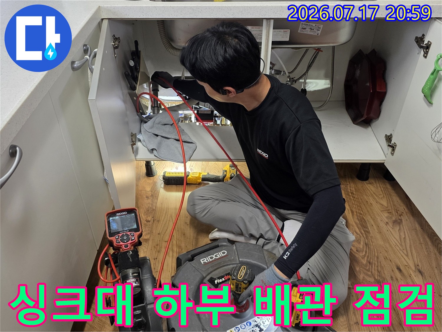엔지니어가 싱크대 아래 공간에서 정밀 장비를 활용해 배수관을 점검하는 모습