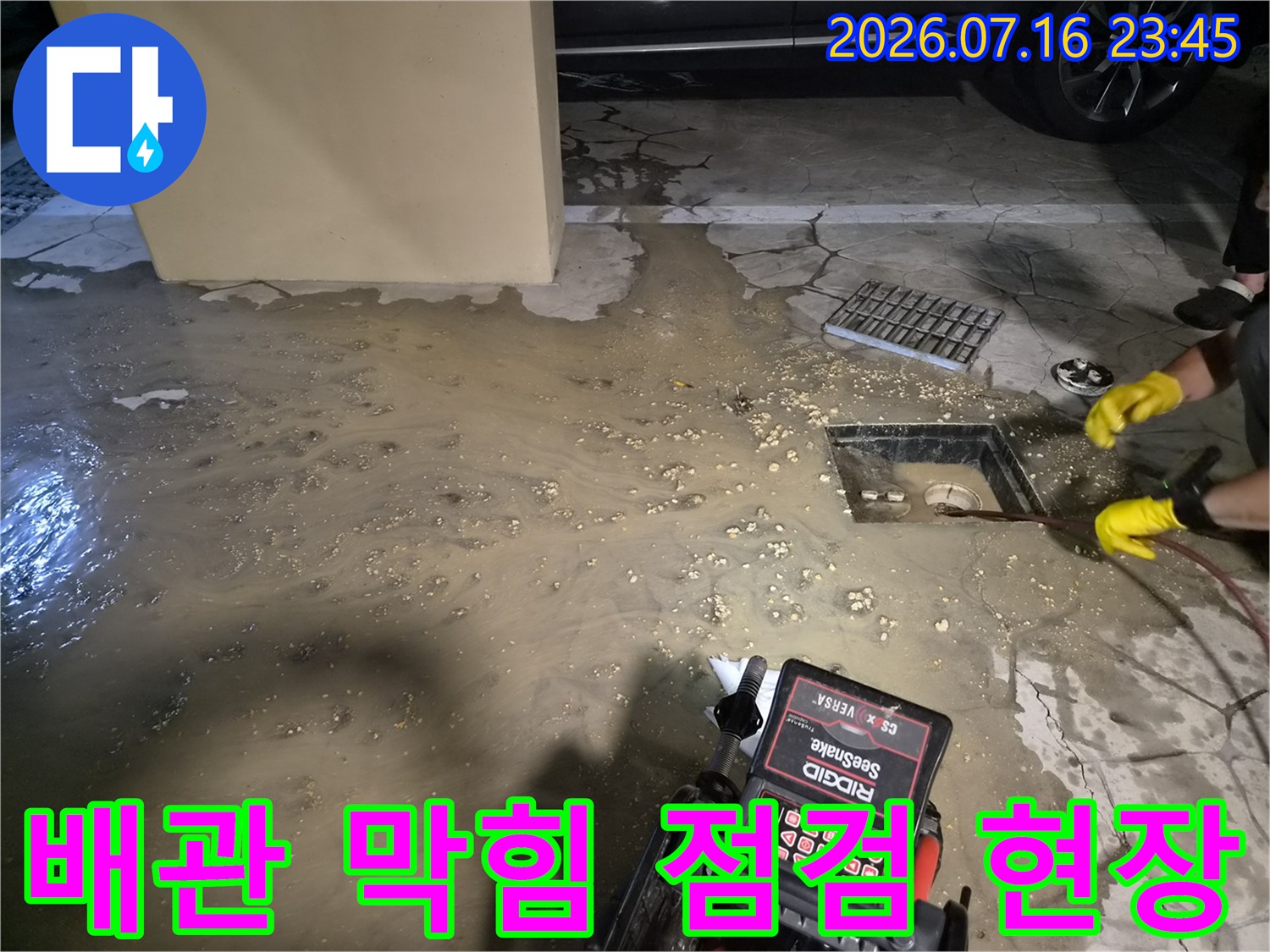 하수구 덮개 주변에 고인 물과 장비가 배치된 배관 점검 현장