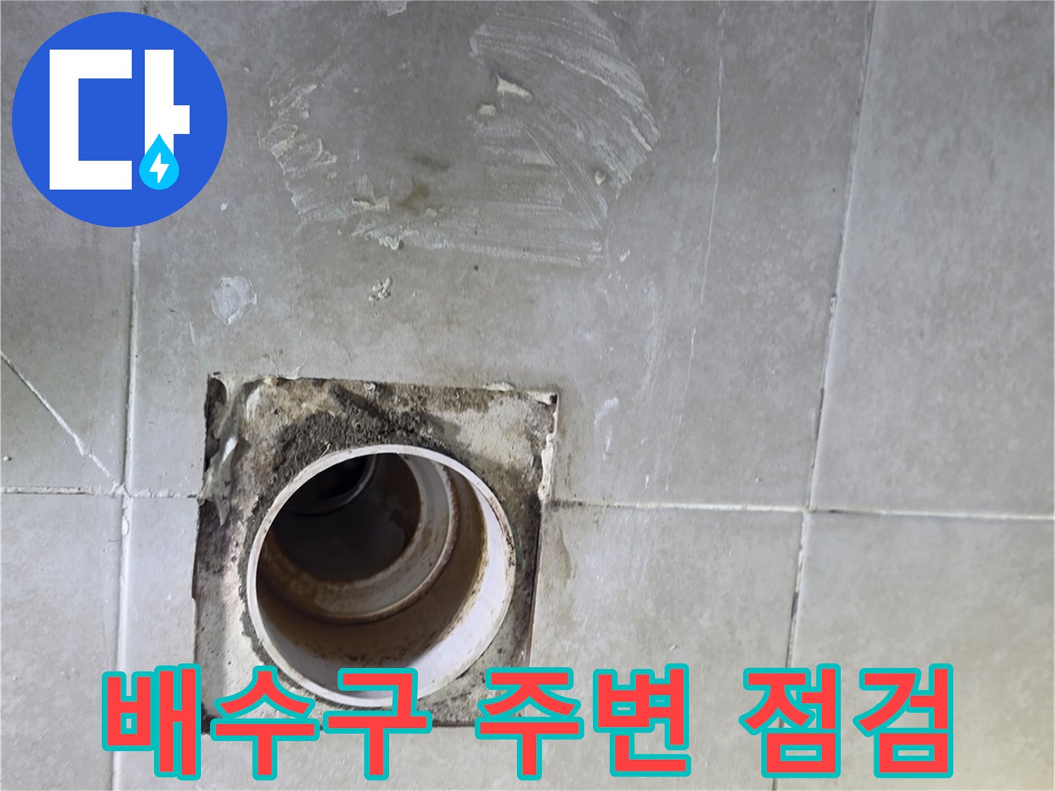 화장실 배수 파이프와 타일 사이의 접합부를 근접 촬영한 사진입니다.