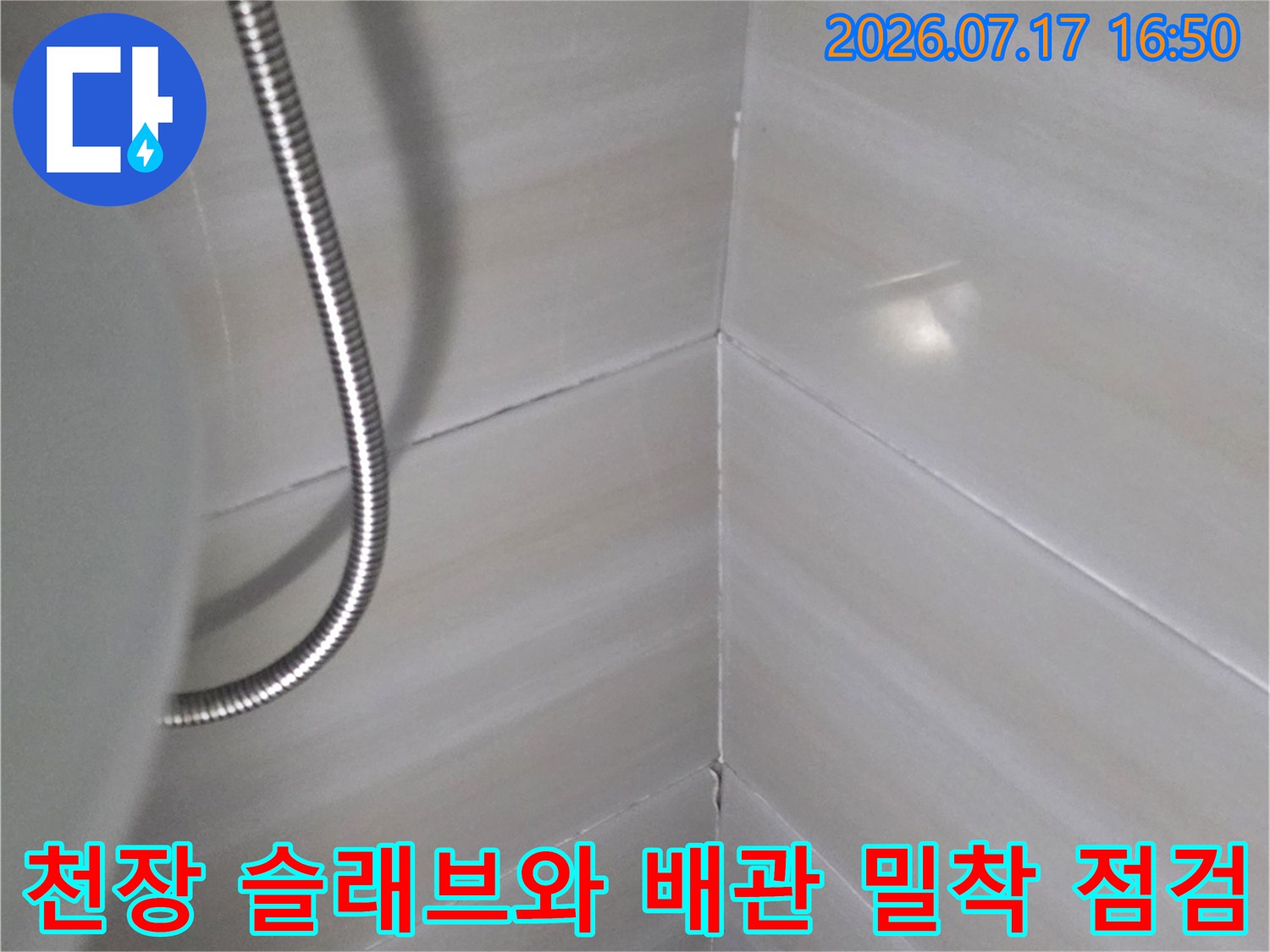 화장실 천장의 흰색 타일 표면과 하단에 배치된 유연한 금속관-전경