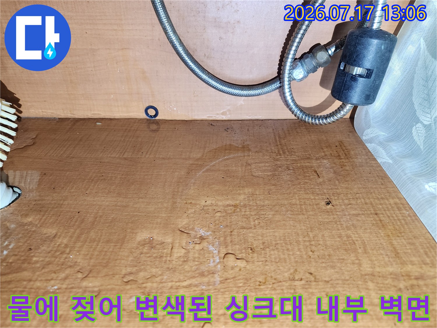 습기에 노출되어 갈색으로 얼룩지고 표면이 상한 주방 하부장의 목재 판넬