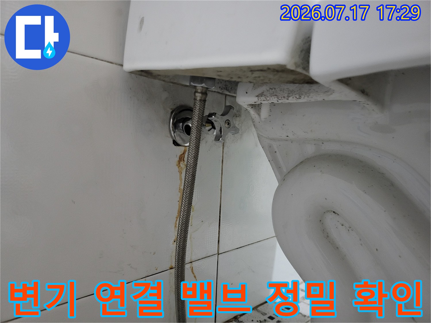 욕실 벽면에 설치된 변기용 수도 밸브와 고압 호스의 연결 부위-근접 촬영