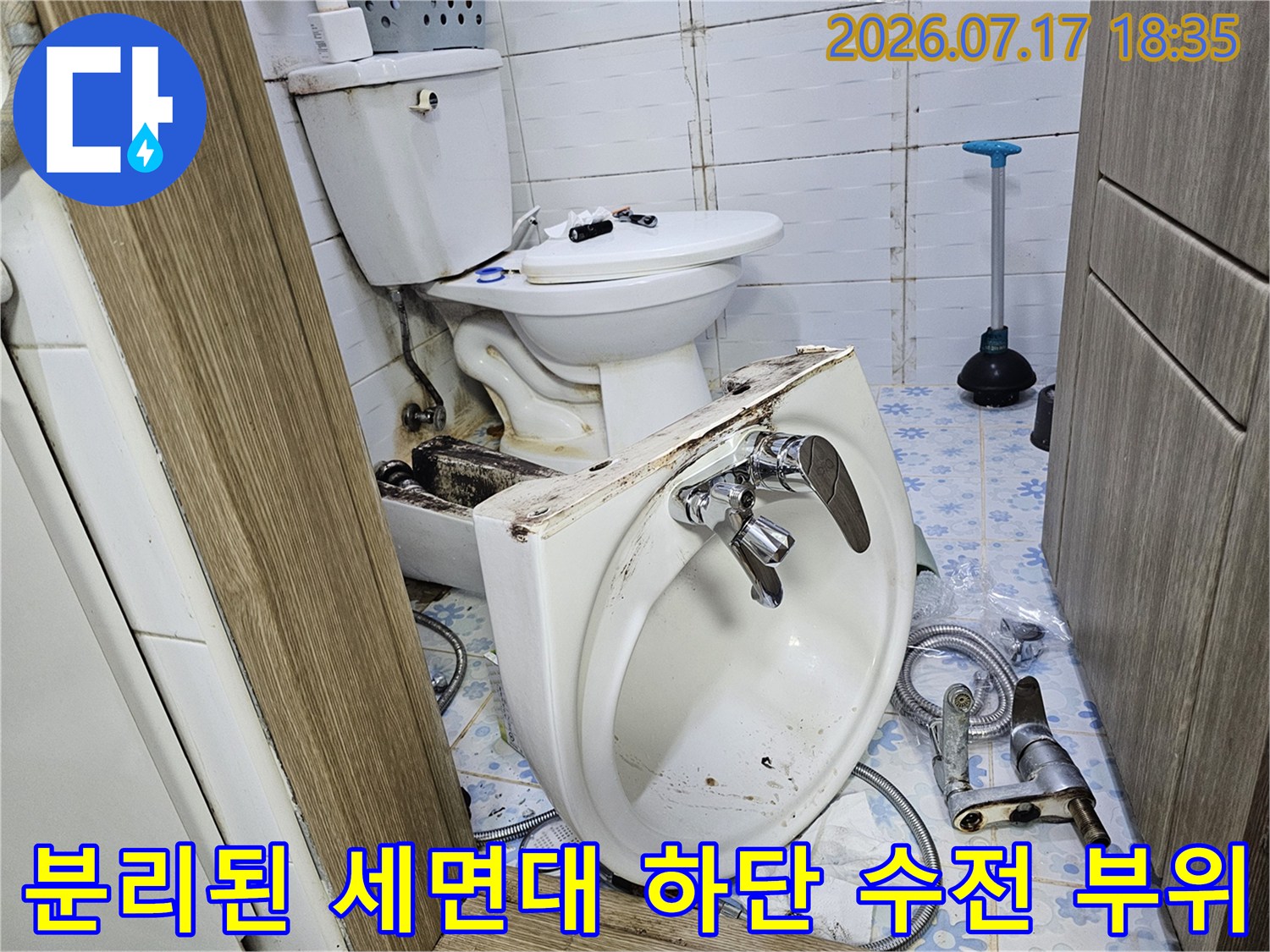 흰색 도기 세면대가 바닥에 놓여 있고-금속제 수전과 급수 호스가 연결되어 있는 모습