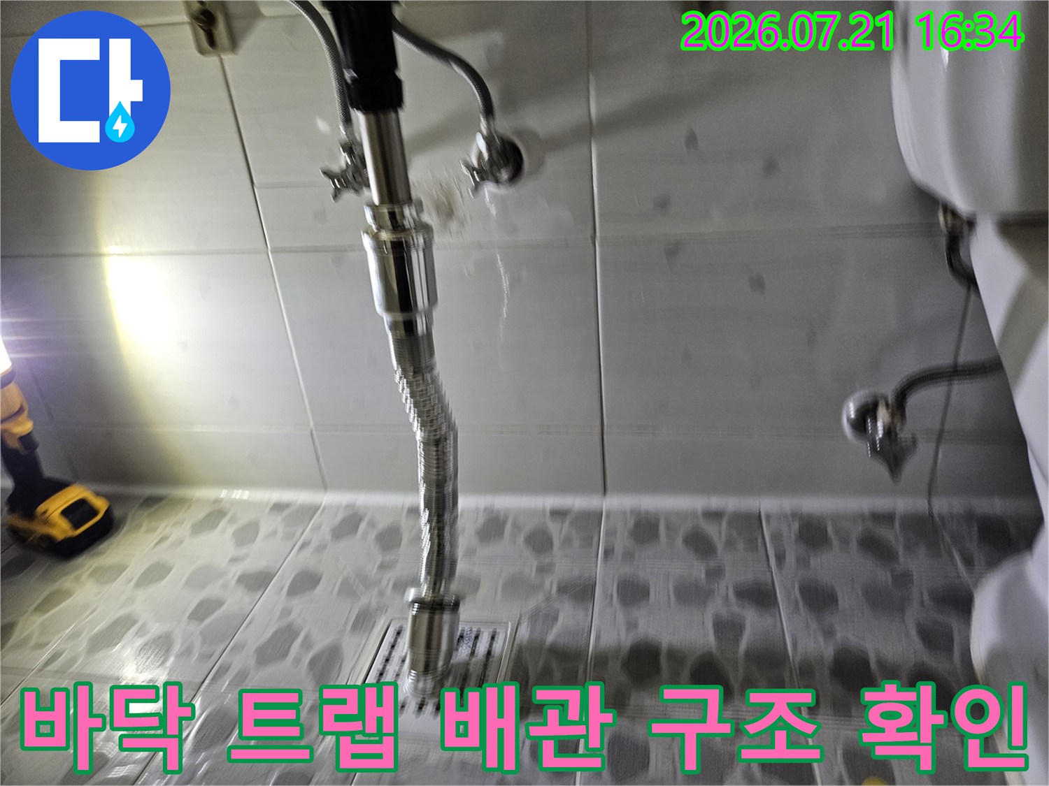 욕실 바닥면의 유연한 배수 호스와 주변 연결부 상태를 점검하는 현장 사진
