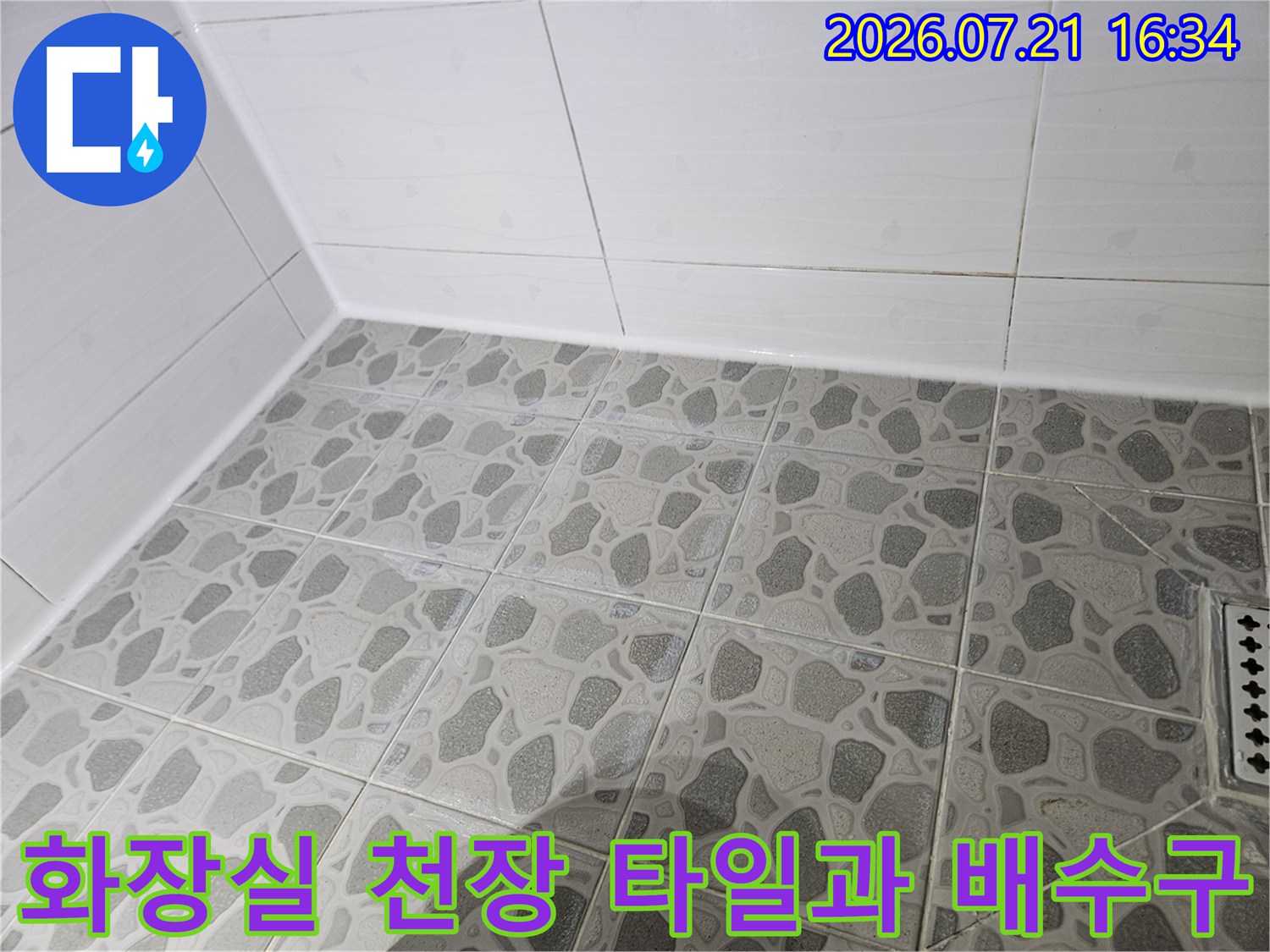 회색 패턴의 화장실 천장 타일과 배수구 주변 모습