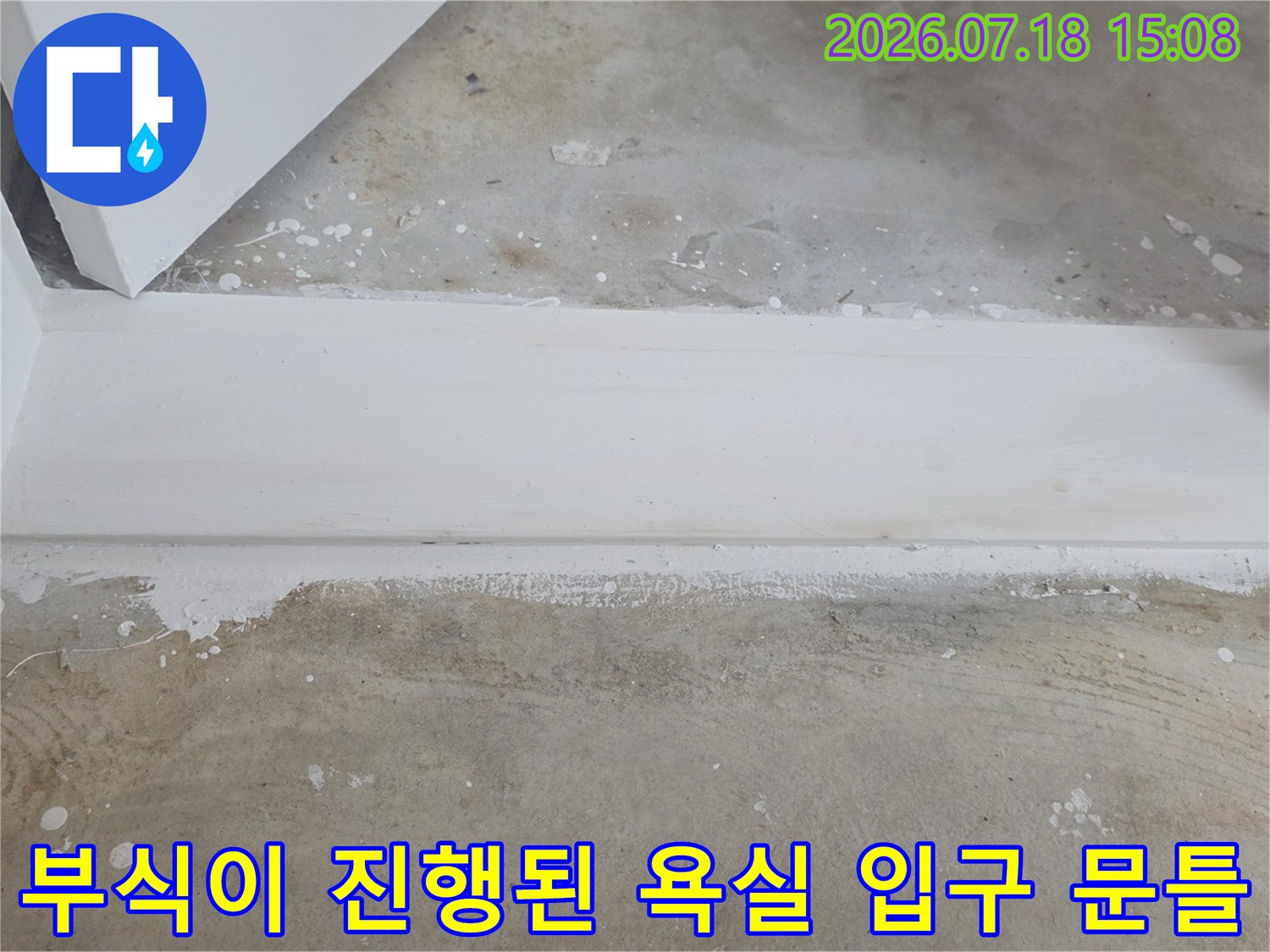 흰색 욕실 문턱의 하단 접합부가 습기로 인해 거뭇하게 변하고 부식된 상세 모습