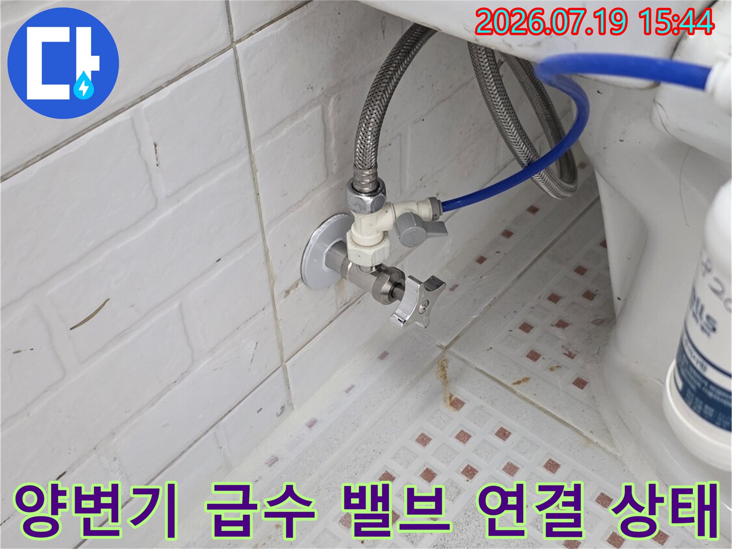 벽면의 은색 주름관과 변기로 들어가는 파란색 호스가 연결된 배관 상세 모습