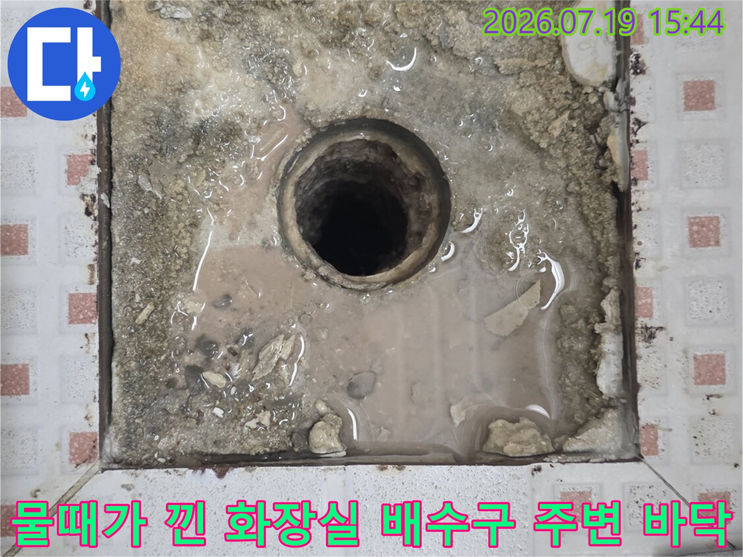 정사각형 모양으로 파낸-화장실 바닥의 배수관과-그 주변에 고인 물 얼룩 사진
