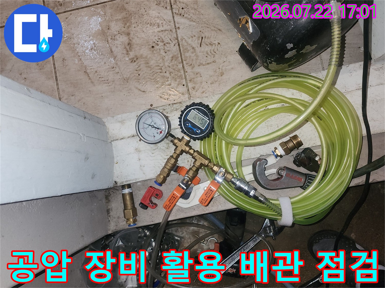 게이지와 호스가 연결된 공압 검사기를 사용하여 배관의 누수 여부를 정밀하게 체크하는 모습