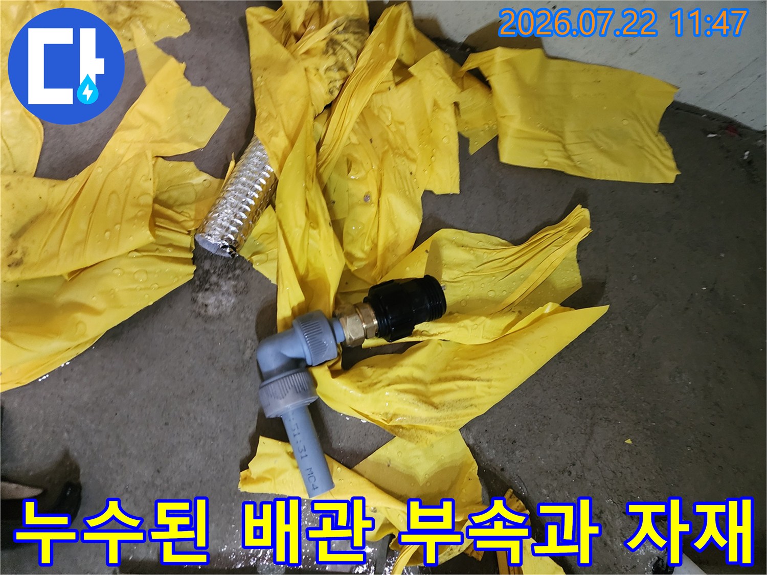 보일러 하단에서 분리되어 나온 파손된 배관-부속-자재들이 노란색 보양지 위에 놓여 있는 모습