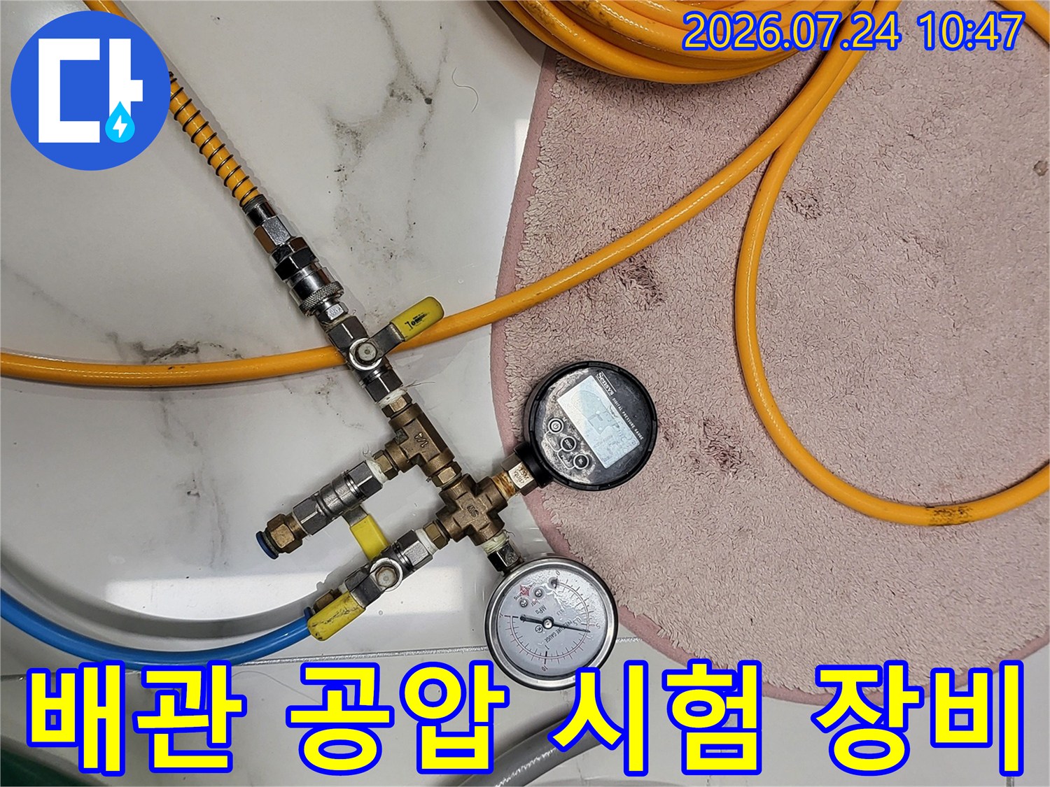 게이지가 연결된 배관 시스템과 노란색 호스의 압력 테스트 장면