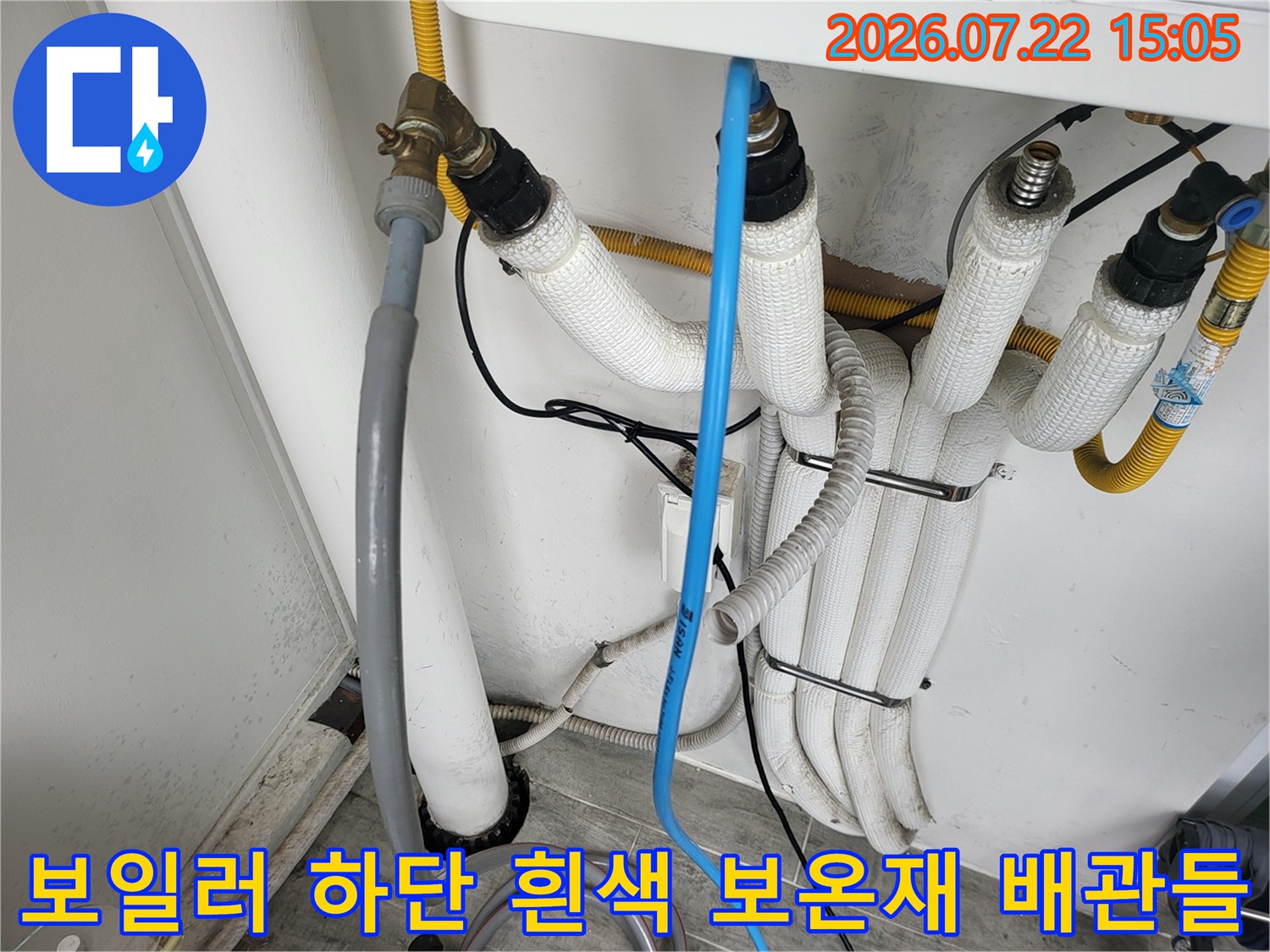 흰색 보온재로 감싸진 보일러 하단 배관 연결 부위와 밸브 모습