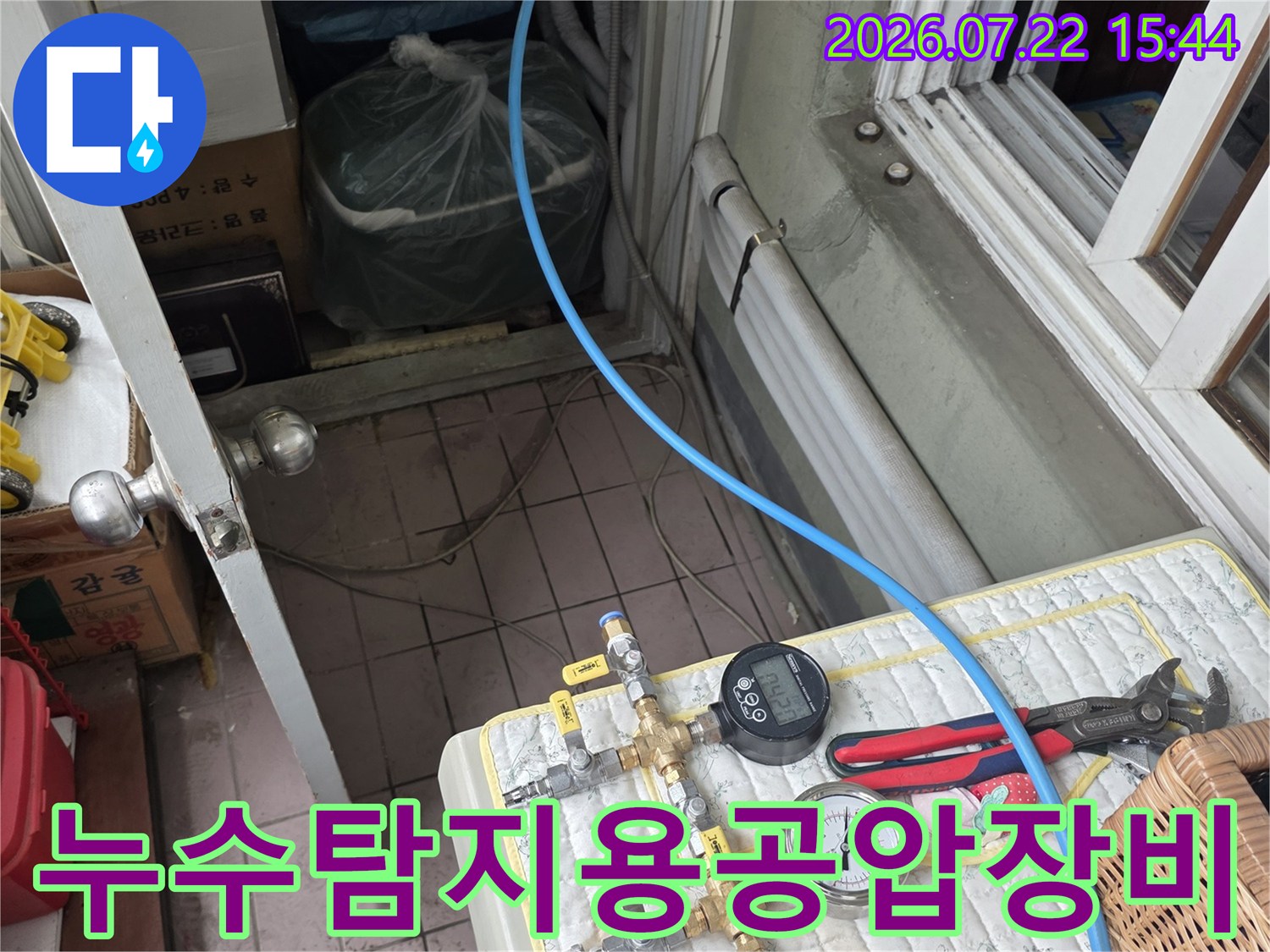 파란색 호스와 압력 측정 게이지가 연결되어 배관 상태를 점검 중인 모습