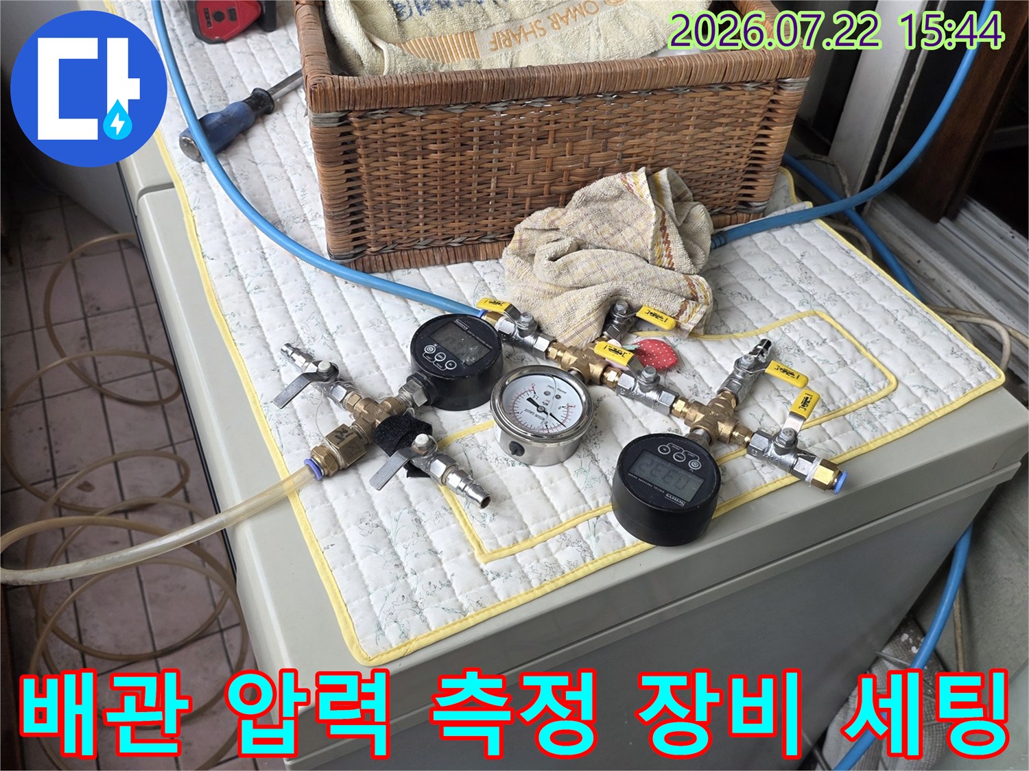 흰색 패드 위에 놓인 정밀 누수 탐지용 공압 테스트 장비와 연결된 파란색 호스