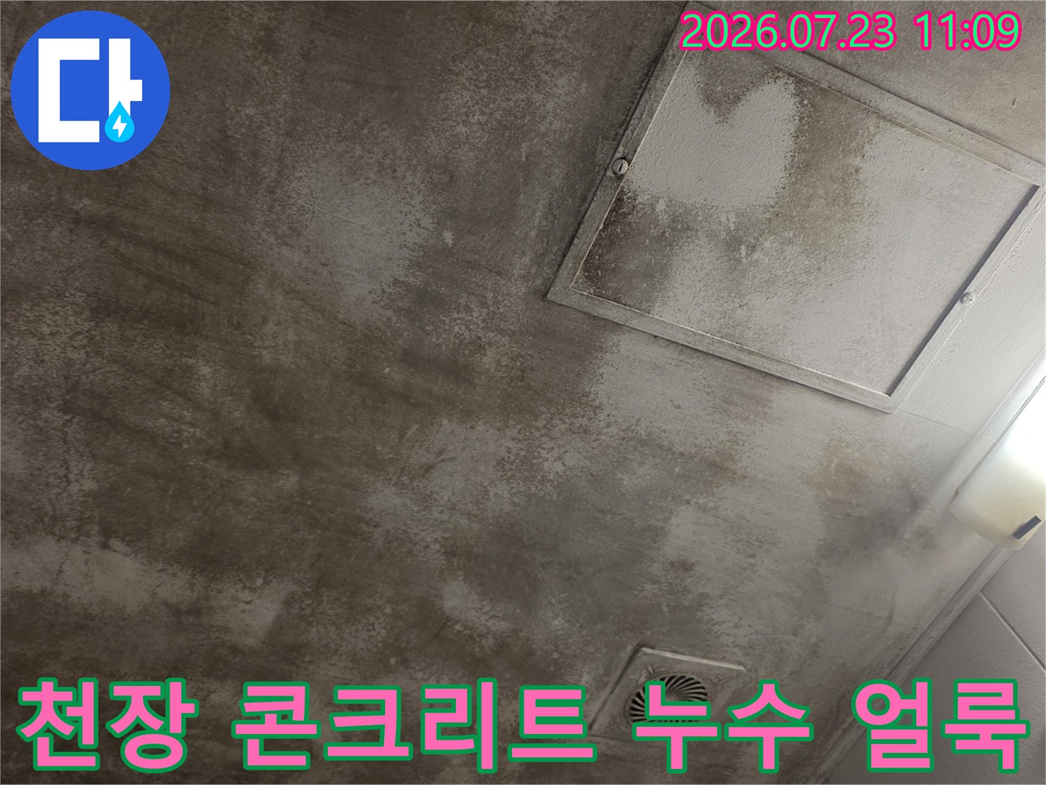 회색 콘크리트 천장에 물이 스며들어 생긴 어두운 얼룩과 점검구 모습