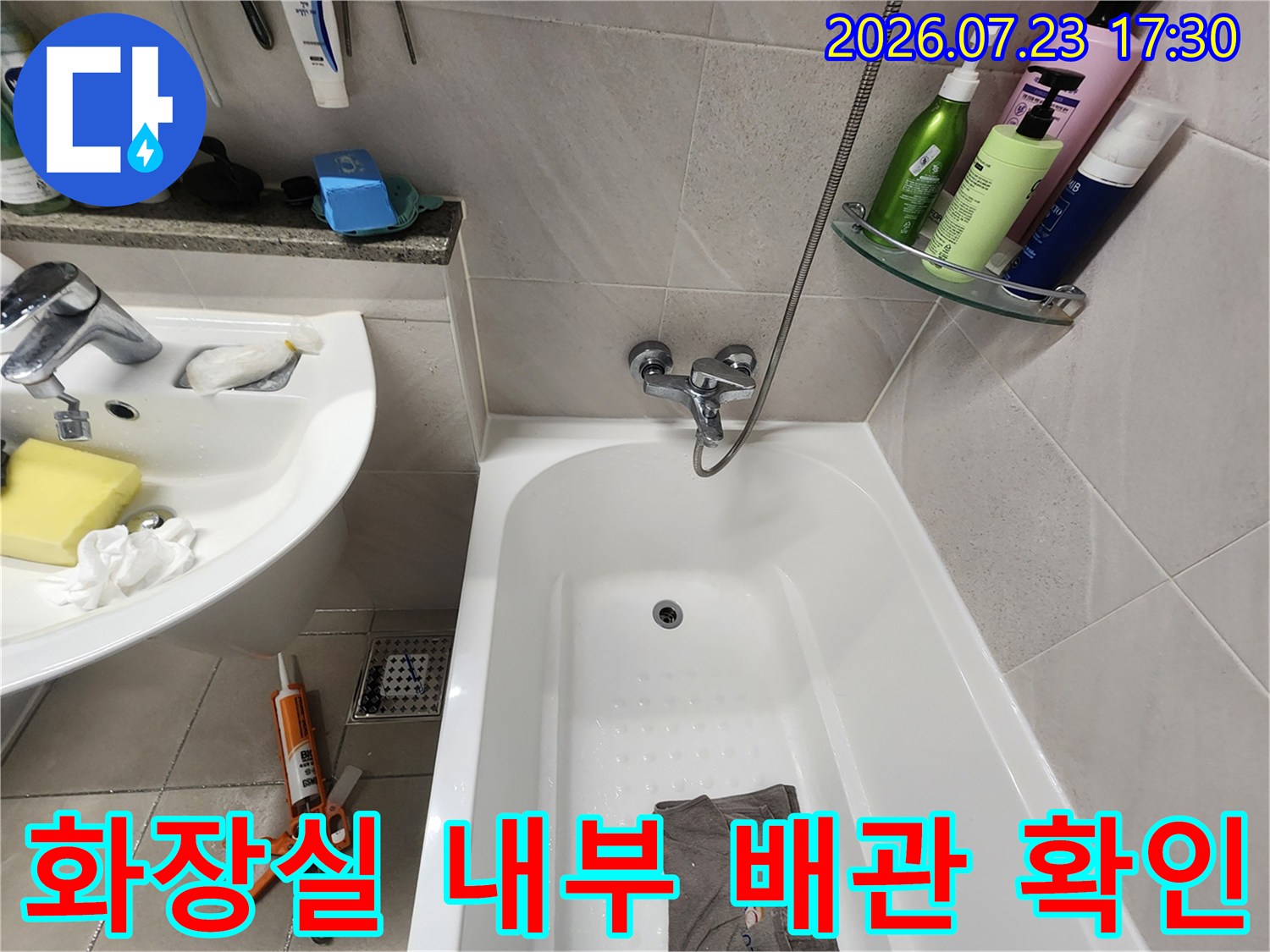 흰색 욕조와 세면대가 설치된-욕실의 전경과 작업 도구 배치 사진