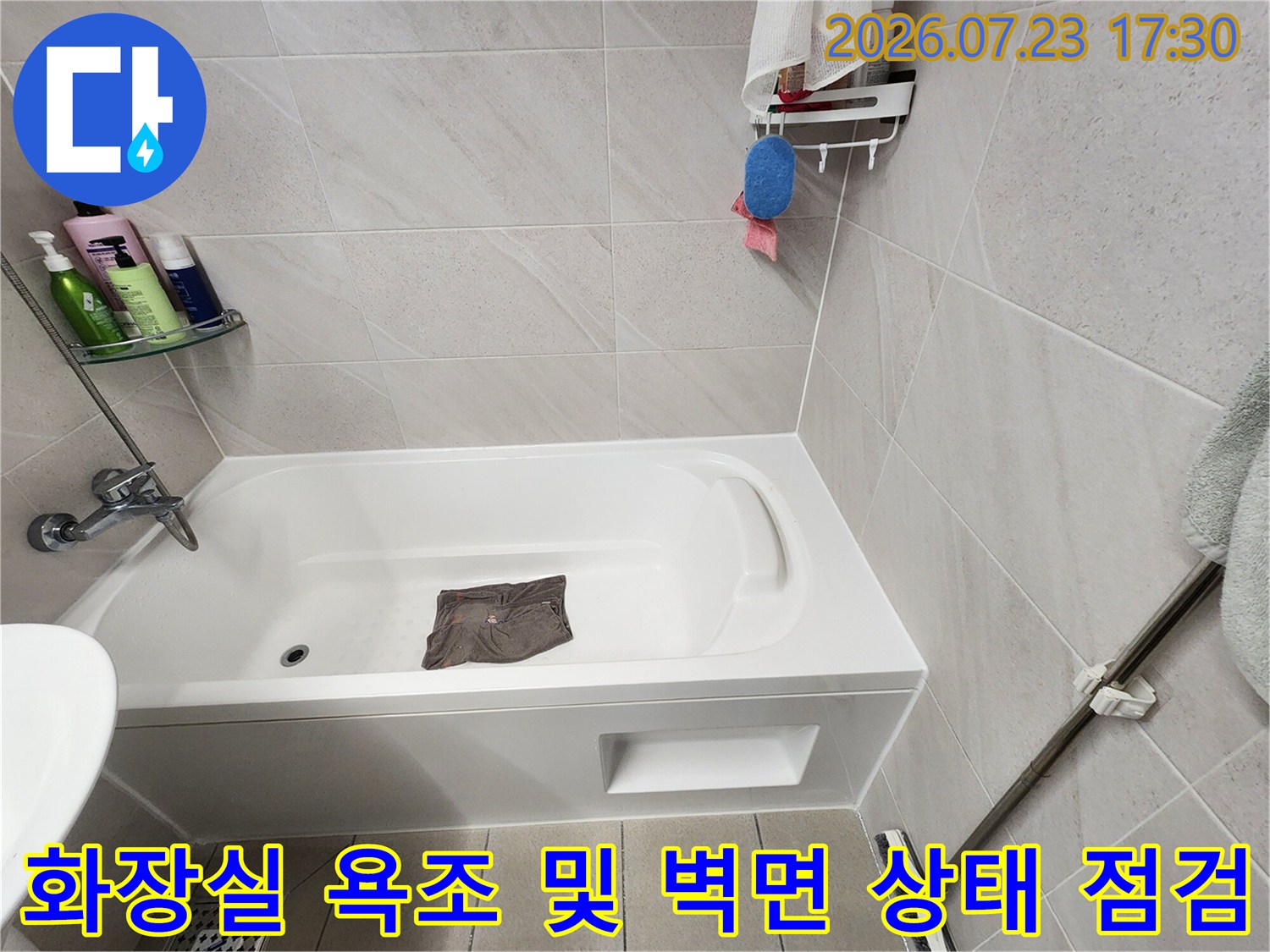 흰색으로 마감된 욕조-주변 회색 타일과 수전이 설치된 화장실 전경