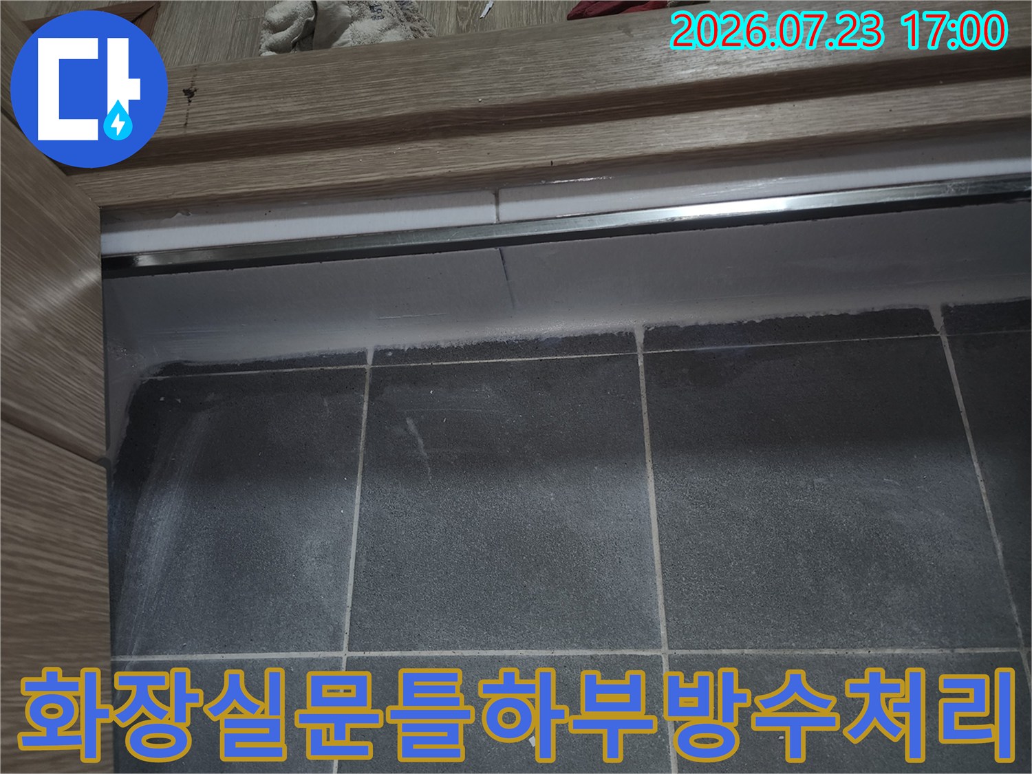 나무-문턱과-그레이-타일-바닥의-접합부를-백색-실리콘으로-마감한-클로즈업-사진