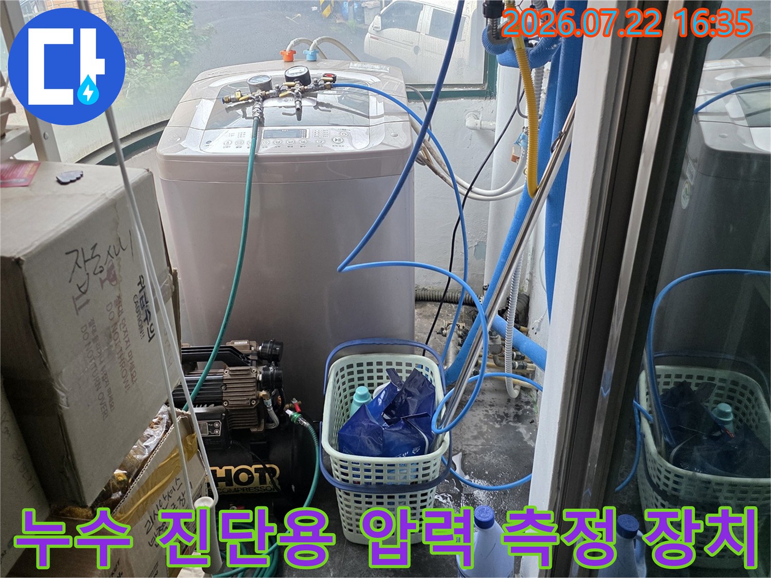 다용도실 바닥에 놓인 누수 탐지 장비와 연결된 파란색 호스들의 모습