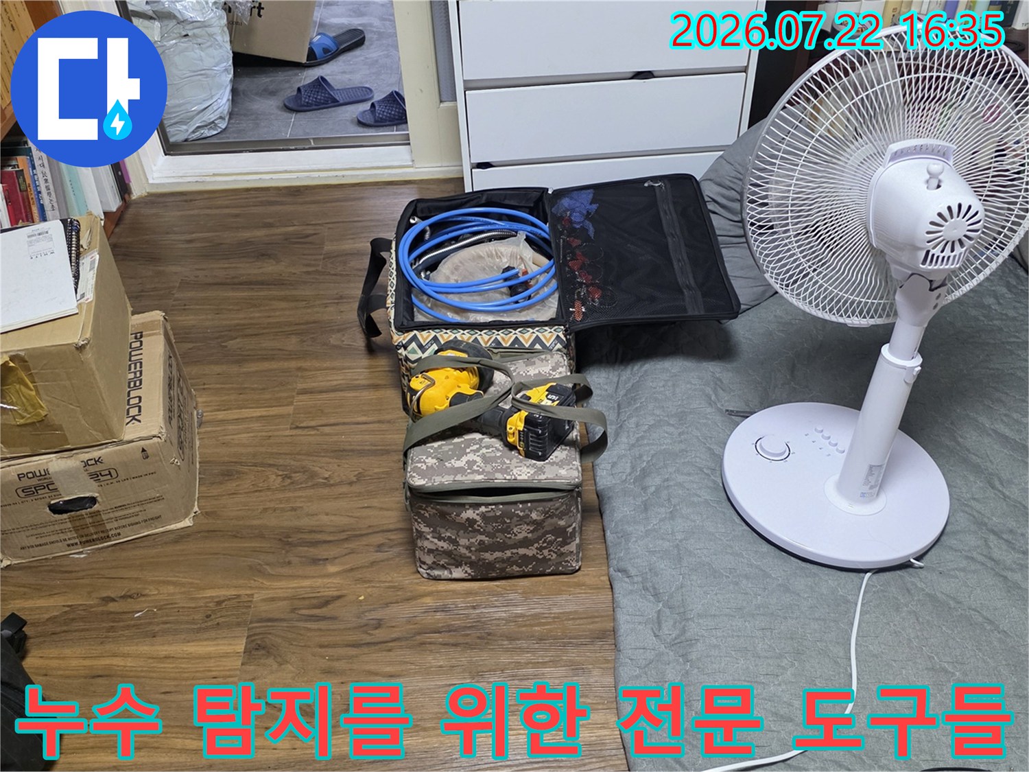 흰색 선풍기 옆에 배치된 누수 탐지 장비-청음기 호스와 공구함 세트
