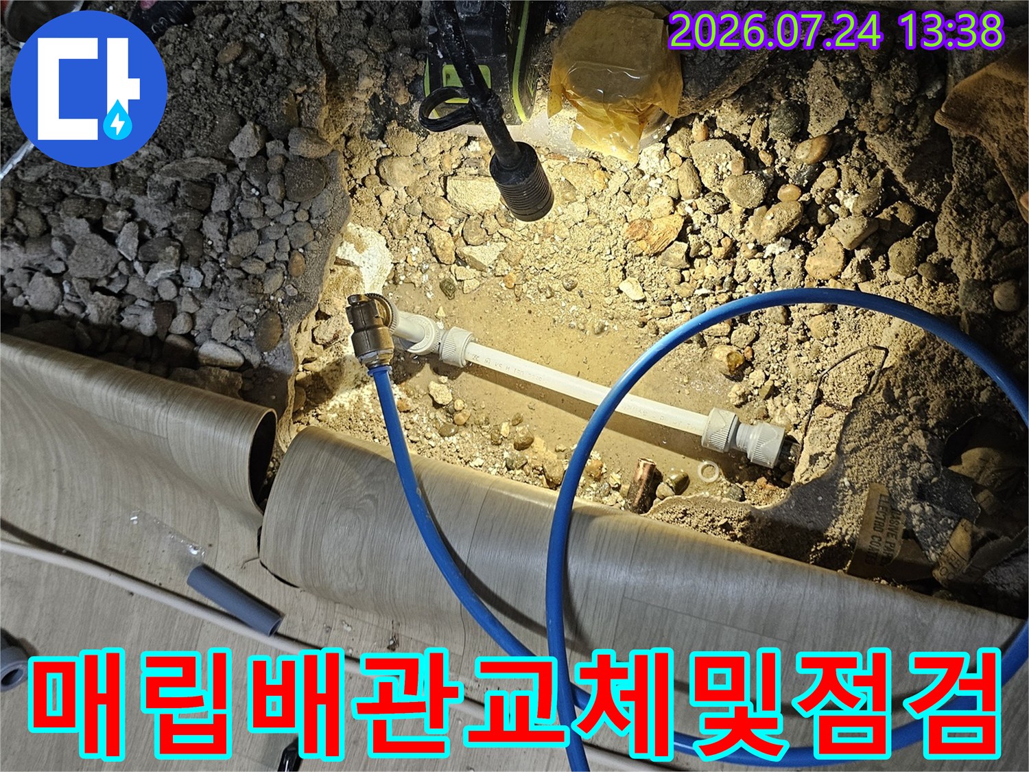 굴착된 바닥면 위로 설치된 새 배관과 누수 점검을 위한 파란색 호스가 연결된 모습