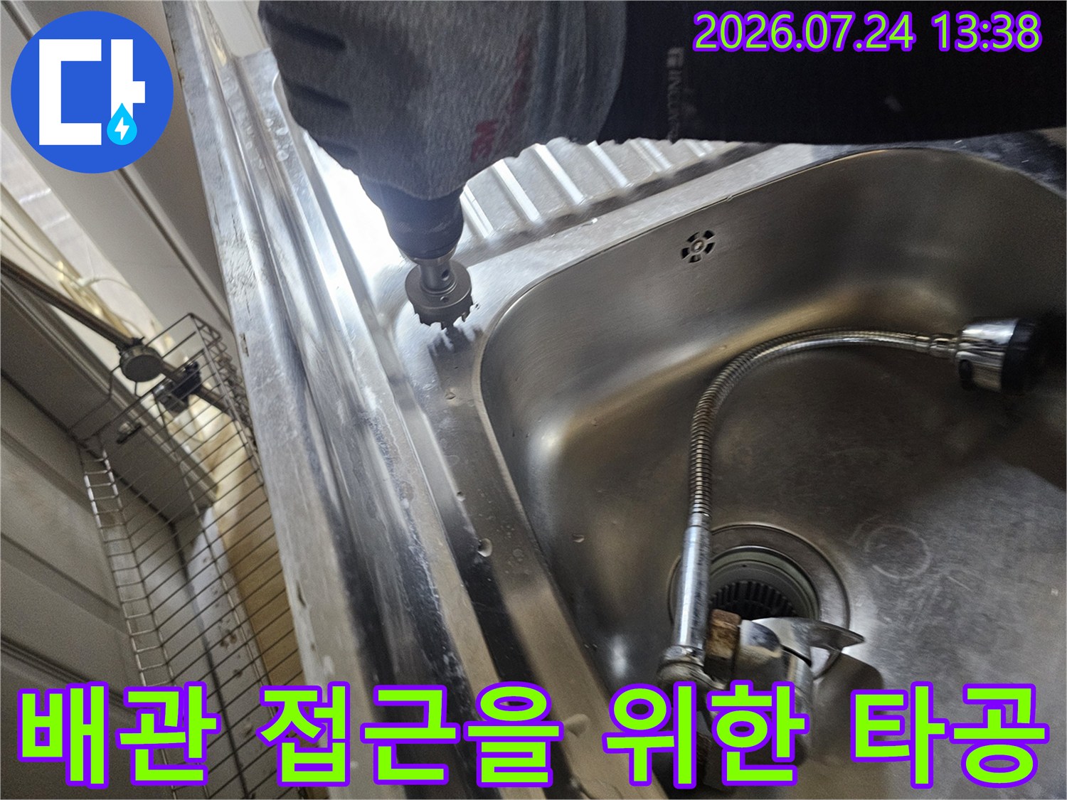 스테인리스 싱크대 볼 주변부를 전동 공구로 타공하여 내부 배관으로 진입하려는 엔지니어의 모습