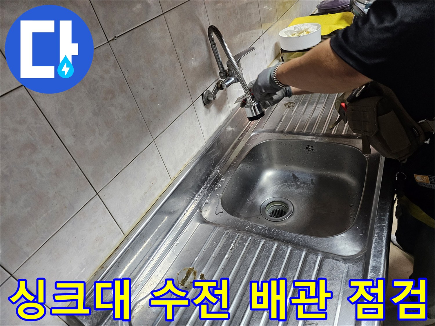 싱크대 하단 배관 연결 부위를 살펴보는 작업 모습