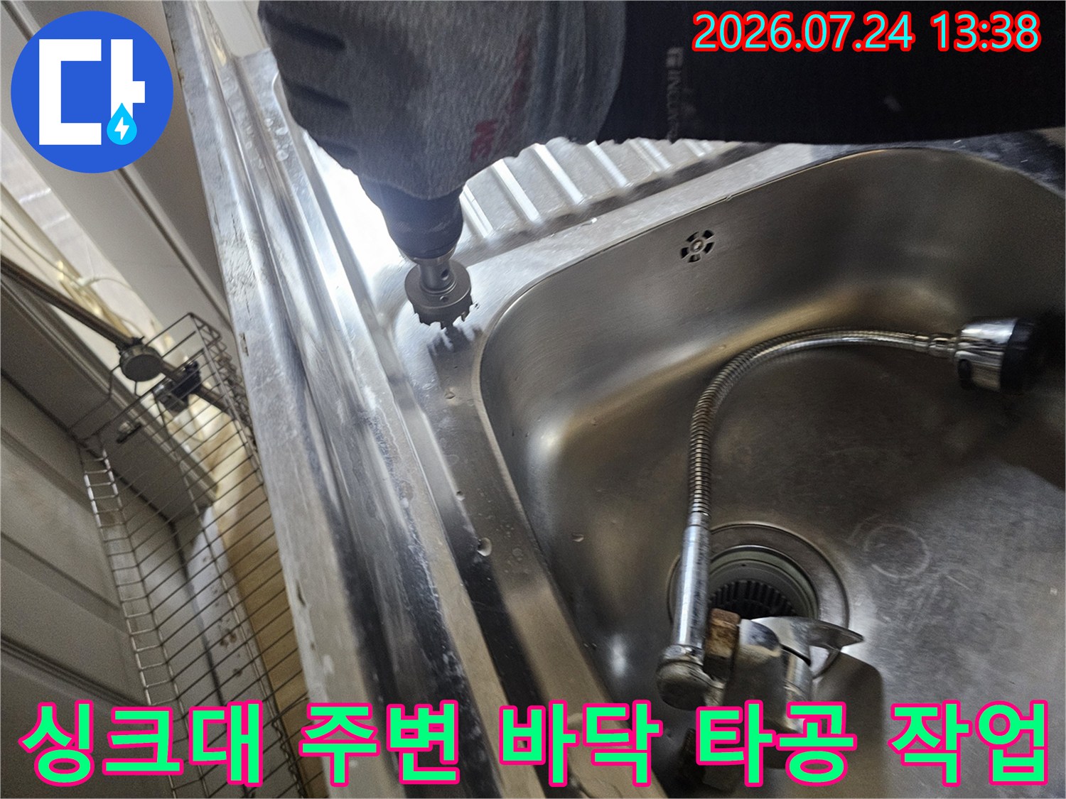 작업자가 전동 드릴 장비를 사용하여 싱크대 옆면 바닥 부분을 정밀하게 타공하는 모습