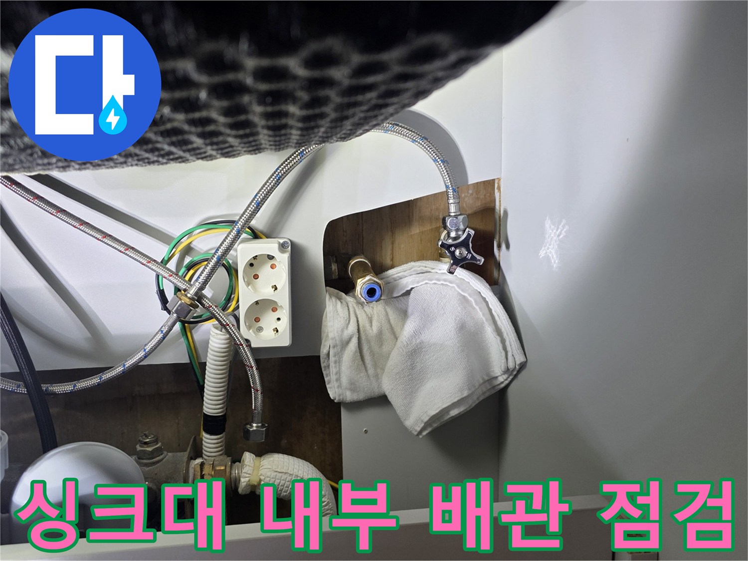 싱크대 하단 배관과 전기 콘센트가 보이는 현장 사진