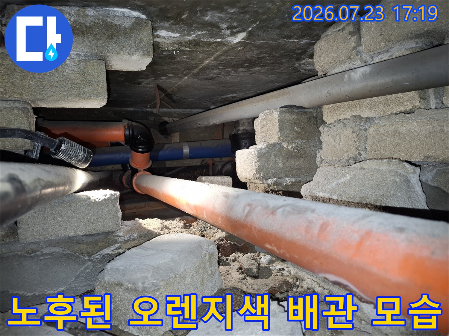 거칠게-부식된-오렌지색 배관과-그 주변의-콘크리트 구조물 사진