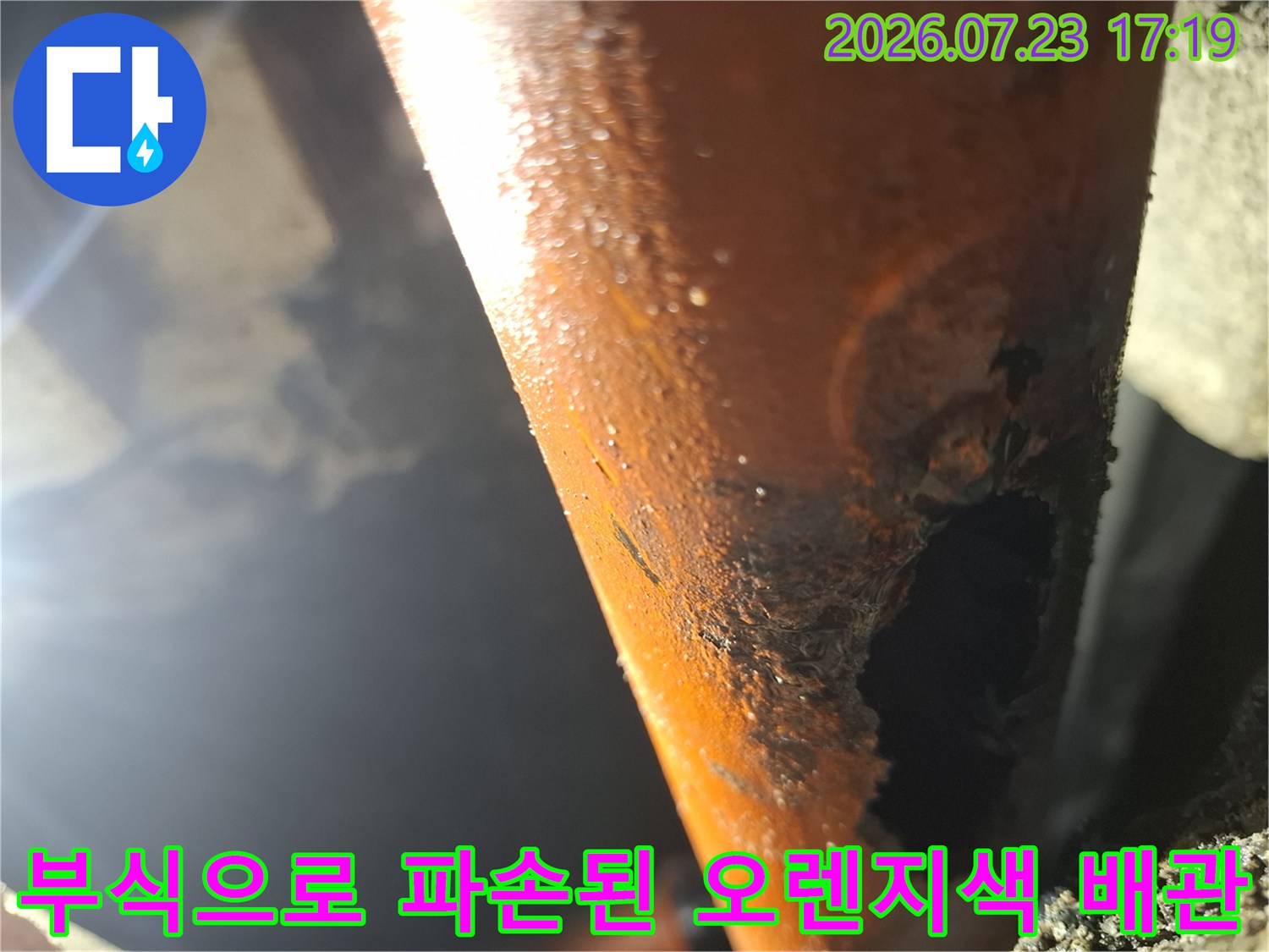 부식이 심해 표면이 거칠고 구멍이 크게 뚫린 주황색 배관의 근접 사진