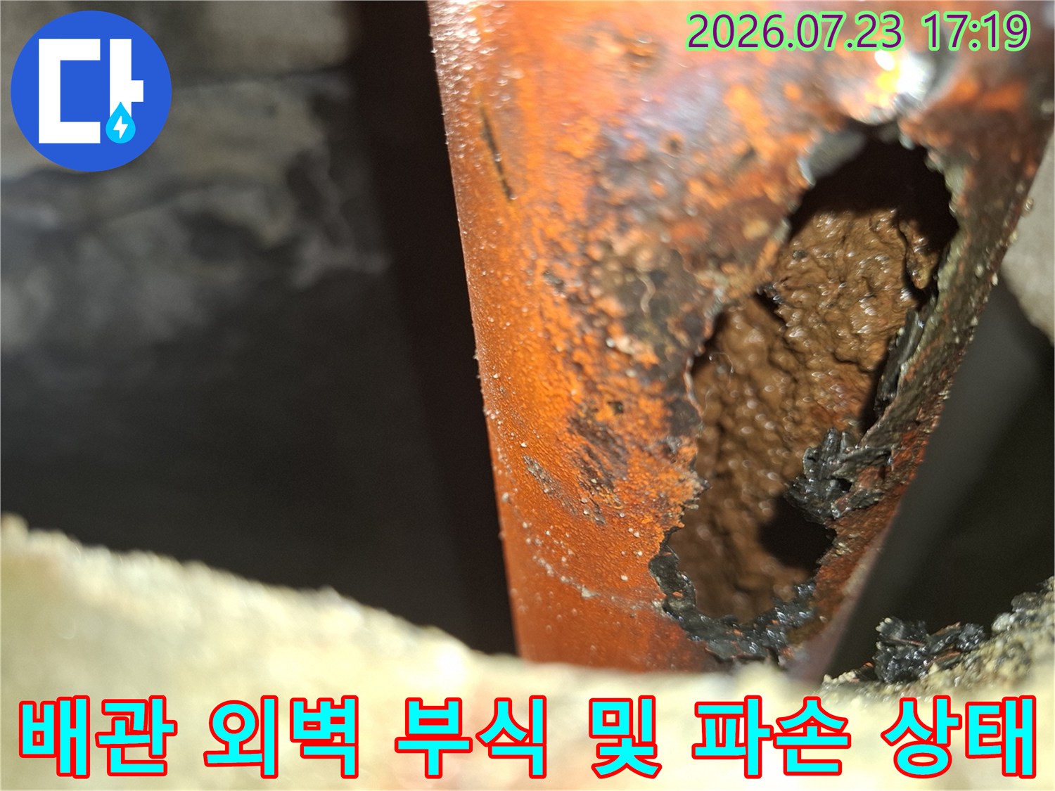 심한 부식으로 인해 외벽이 손실되어 내부가 드러난 오렌지색 배관의 모습