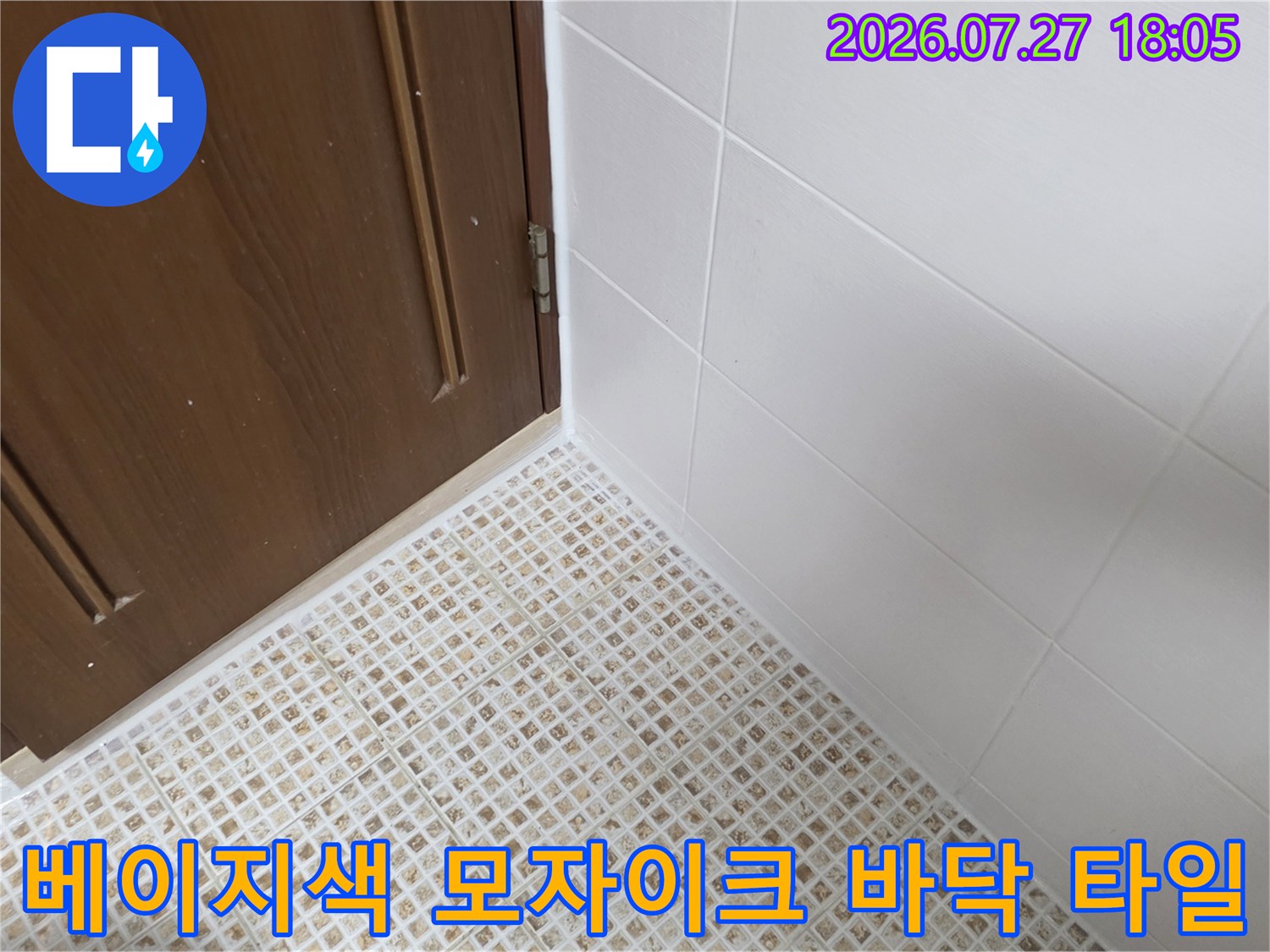 갈색 나무 문과 하얀 벽면-그리고 바닥에 시공된 작은 사각형 패턴의 베이지색 욕실 타일 전경