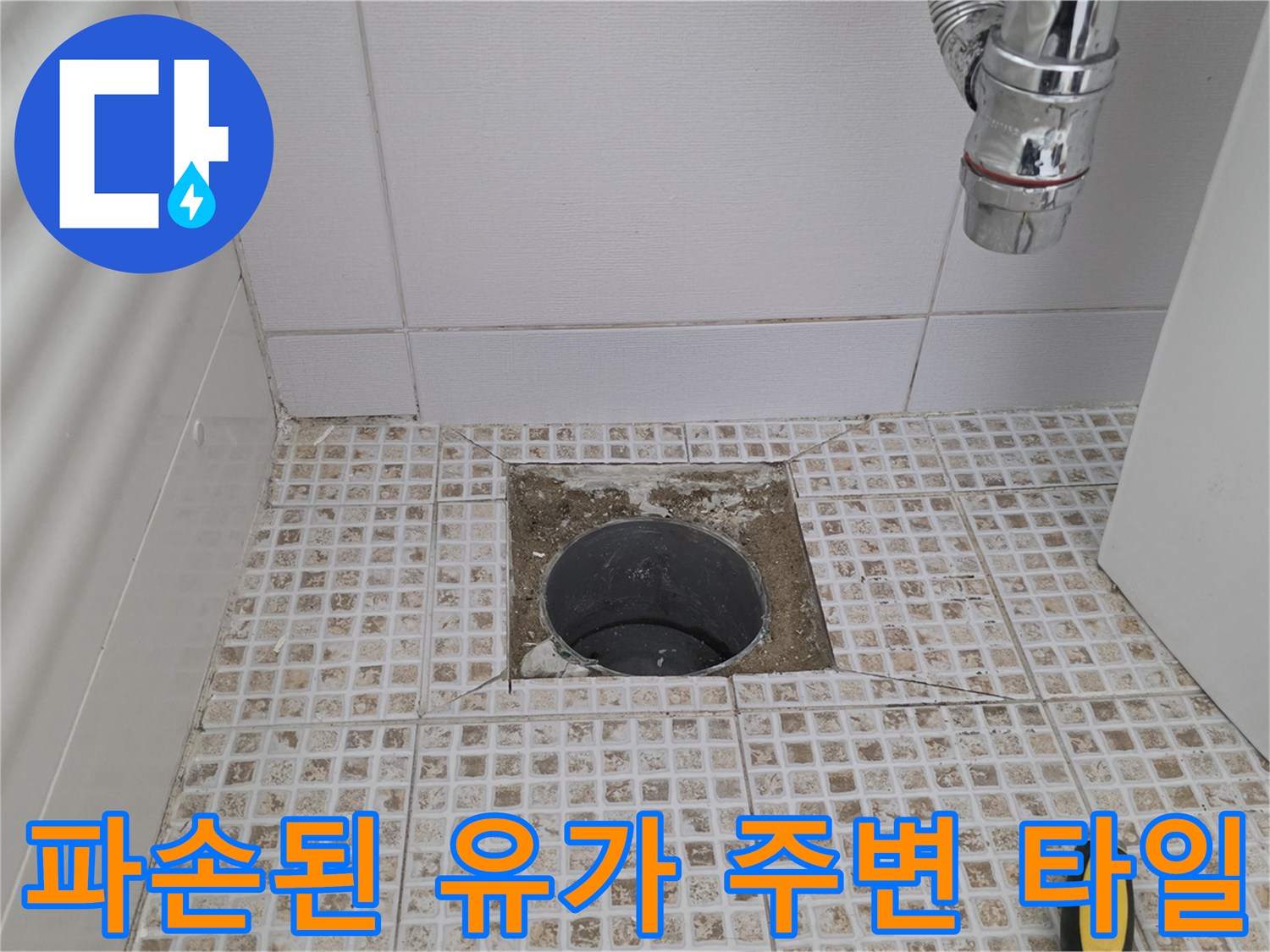배수구 입구의 파손된 타일과 노출된 배관 내부