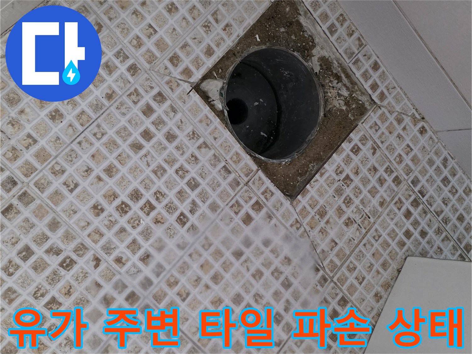 화장실 배수구 주변의 깨진 타일과 벌어진 틈새를 보여주는 사진