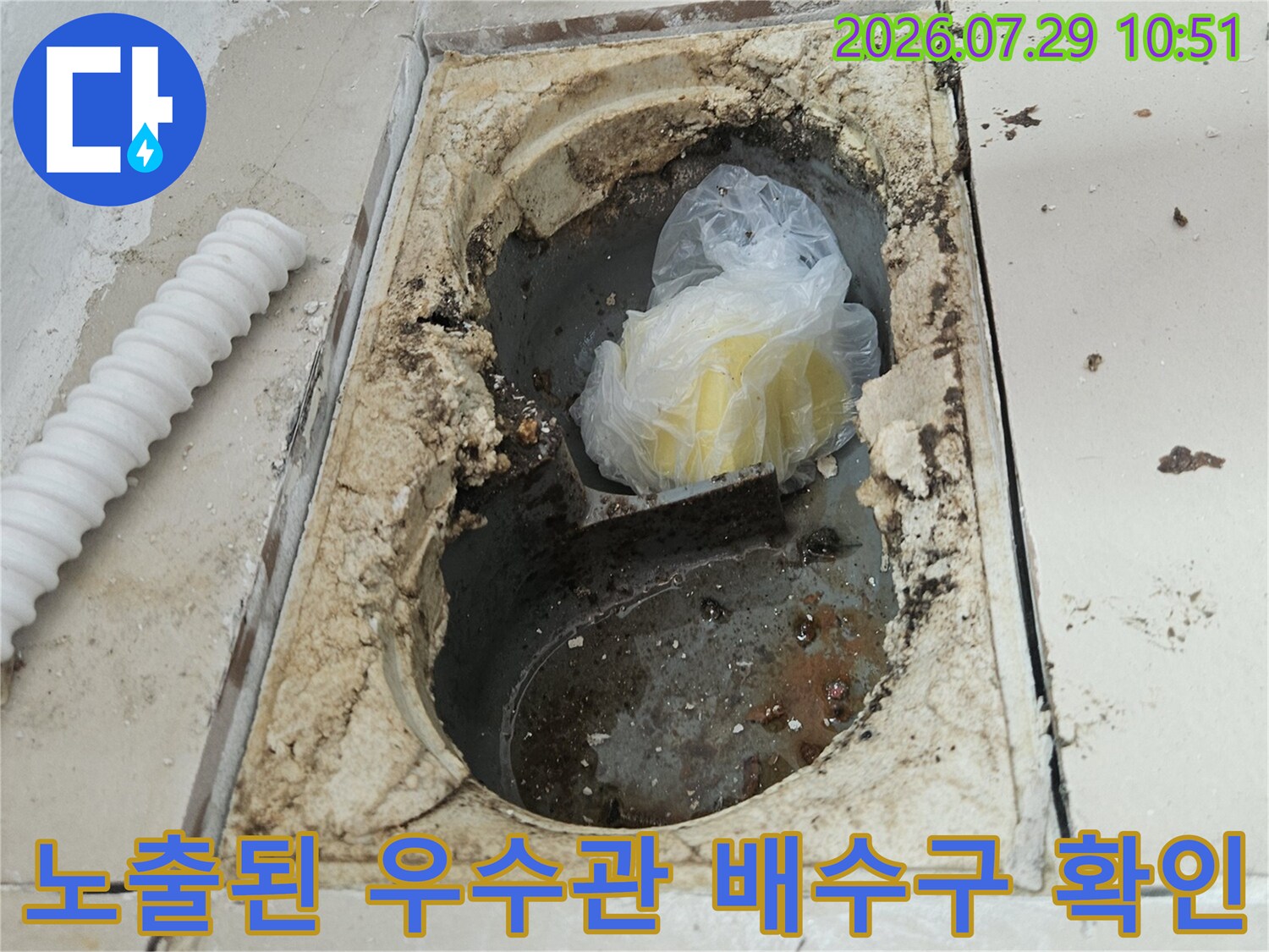 손상된 타일 사이로 노출된 베란다 우수관과 배수구 내부 모습