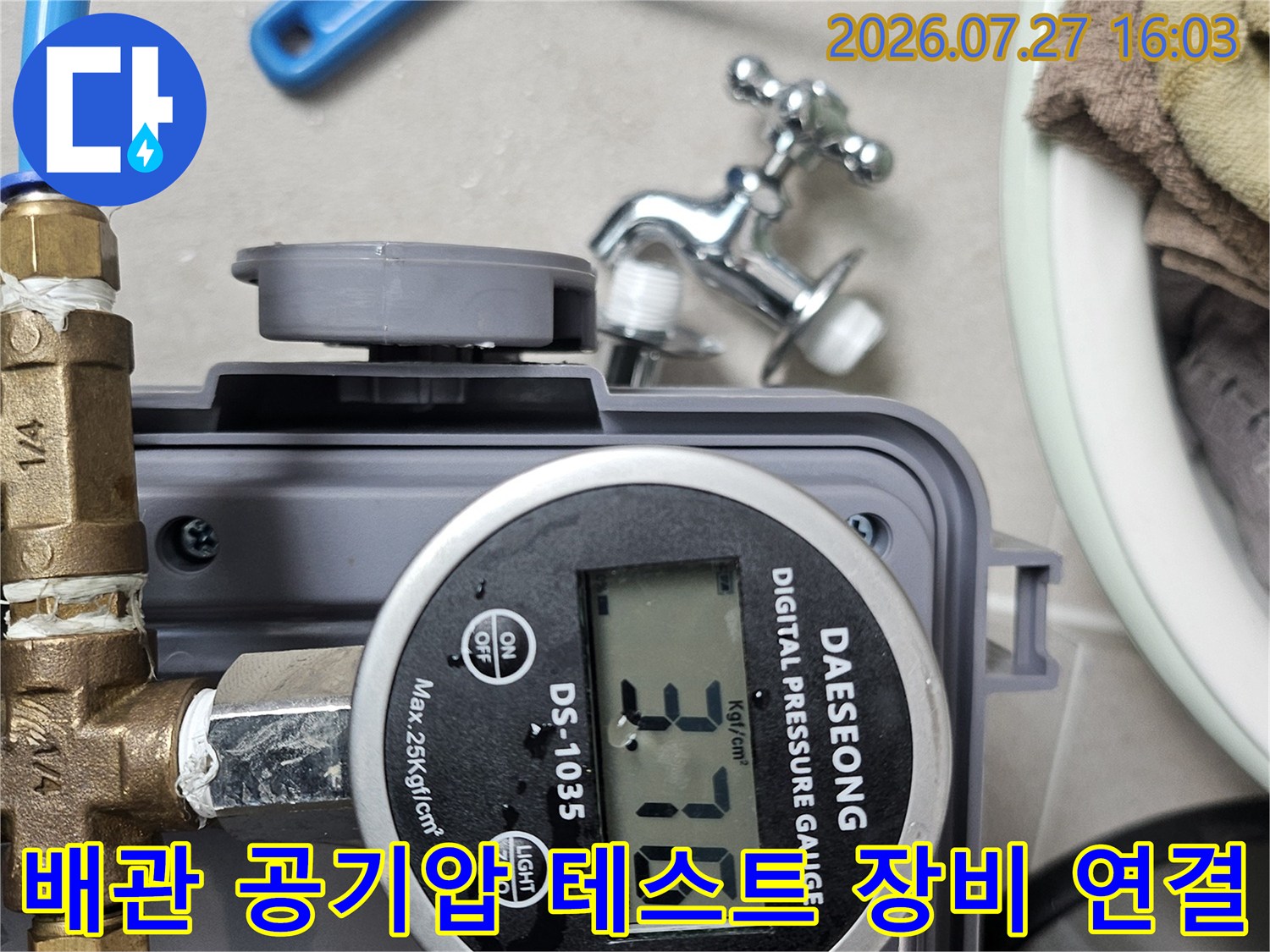 파란색 호스와 황동 밸브가 연결된 디지털 압력 측정기의 숫자가 표시된 모습