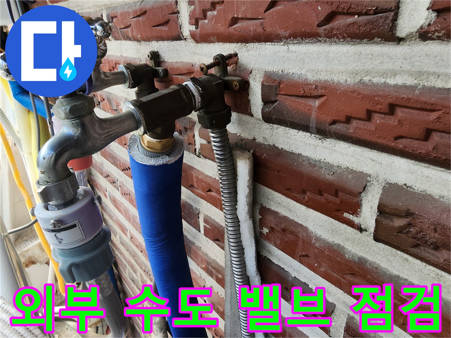 벽돌 외벽에 설치된 금속 수도 밸브와 보온 배관