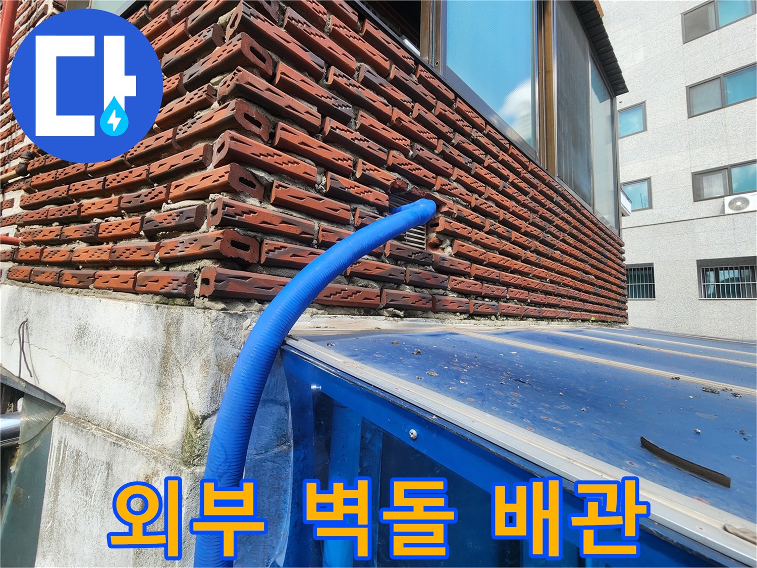 붉은색 벽돌 사이로 노출된 파란색 보온재 배관의 모습