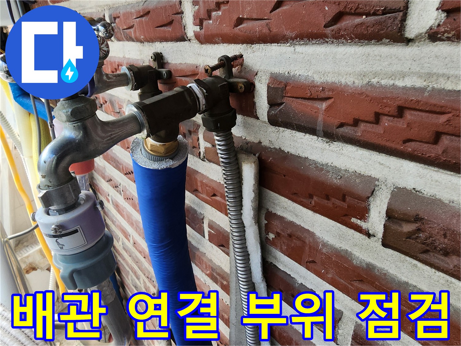 외벽 벽돌 사이로 돌출된 수도꼭지와 보온재가 씌워진 배관의 모습입니다.