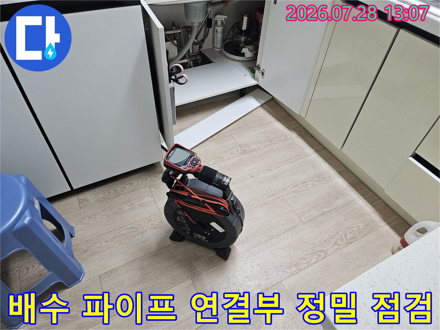 싱크대 밑 배수관의 마감 상태를 세심하게 살피는 공사 현장 사진