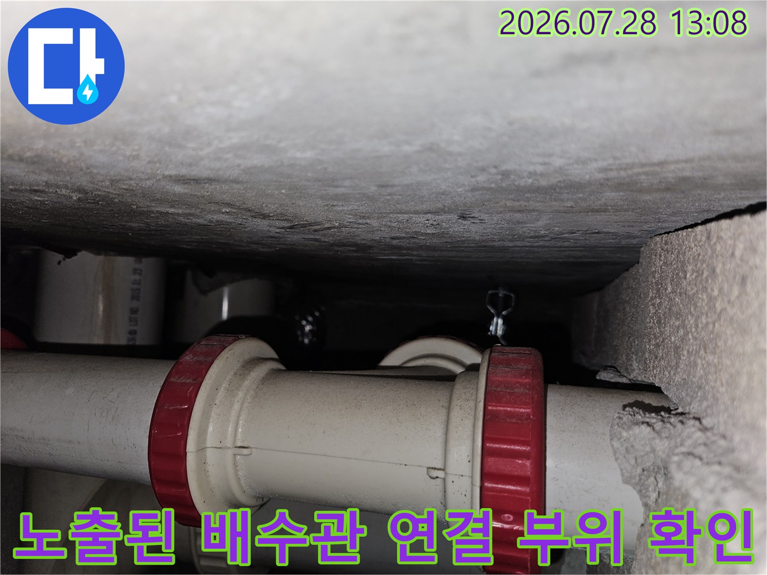 어둡고 좁은 공간 내에 노출된 하수관 접합부를 수리하기 전 점검하는 장면