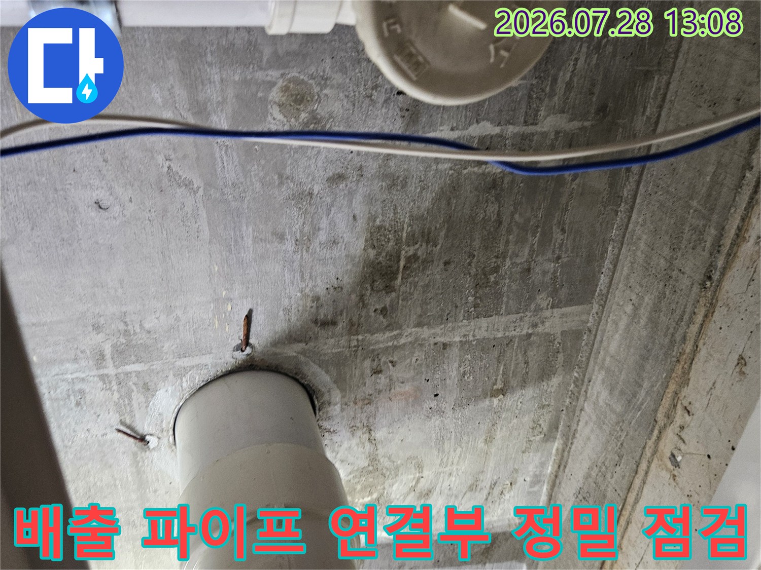 하얀색 배수관과 벽면 접합 부위의 상태를 면밀히 살피는 기술자의 모습