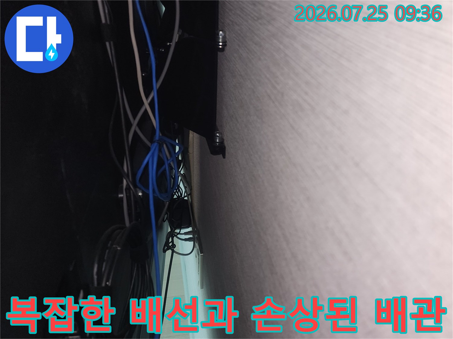 거실 가전제품 뒤편의 복합적인 설비와 배선 상태를 촬영한 사진
