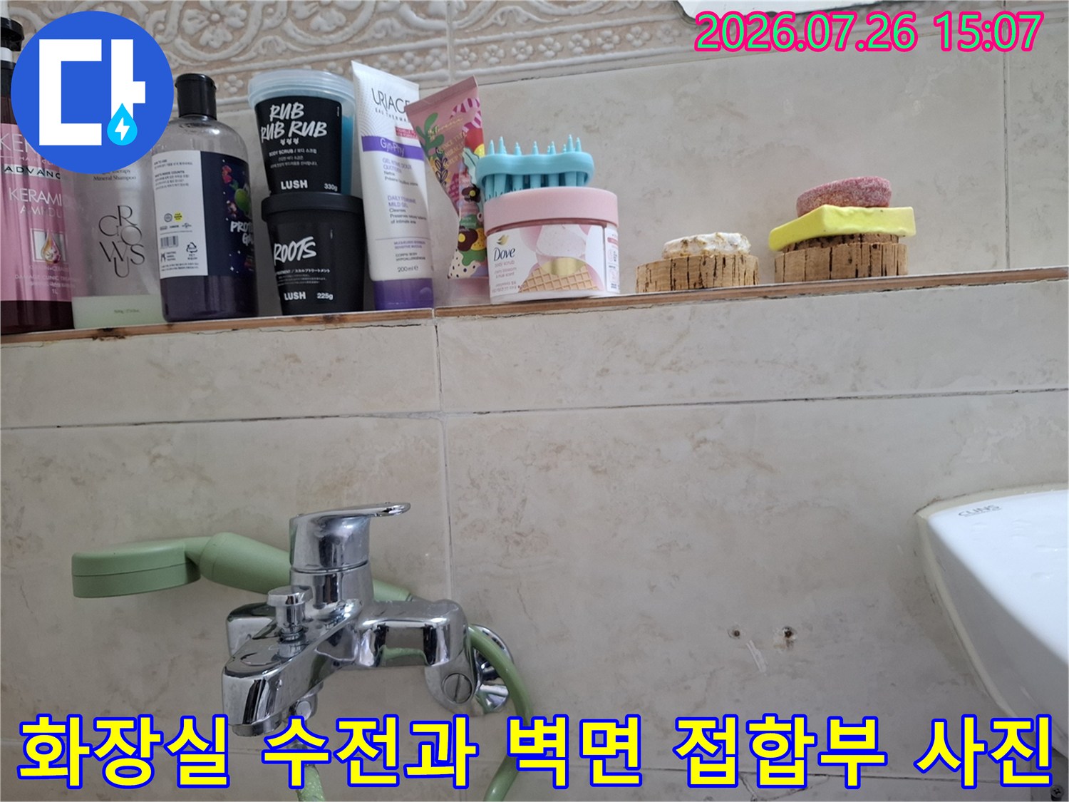 은색 수도꼭지와 연결된 배관-주변 베이지톤 타일 마감재의 상세 모습