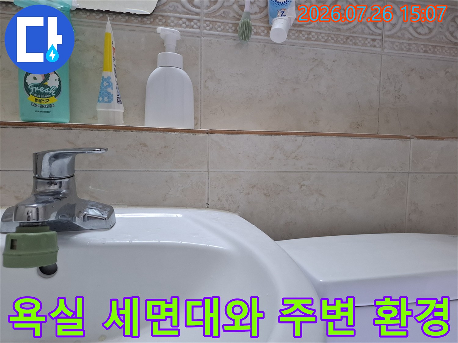크롬 소재의 수도꼭지가 설치된 흰색 세면대-베이지 톤 타일 벽면 사진
