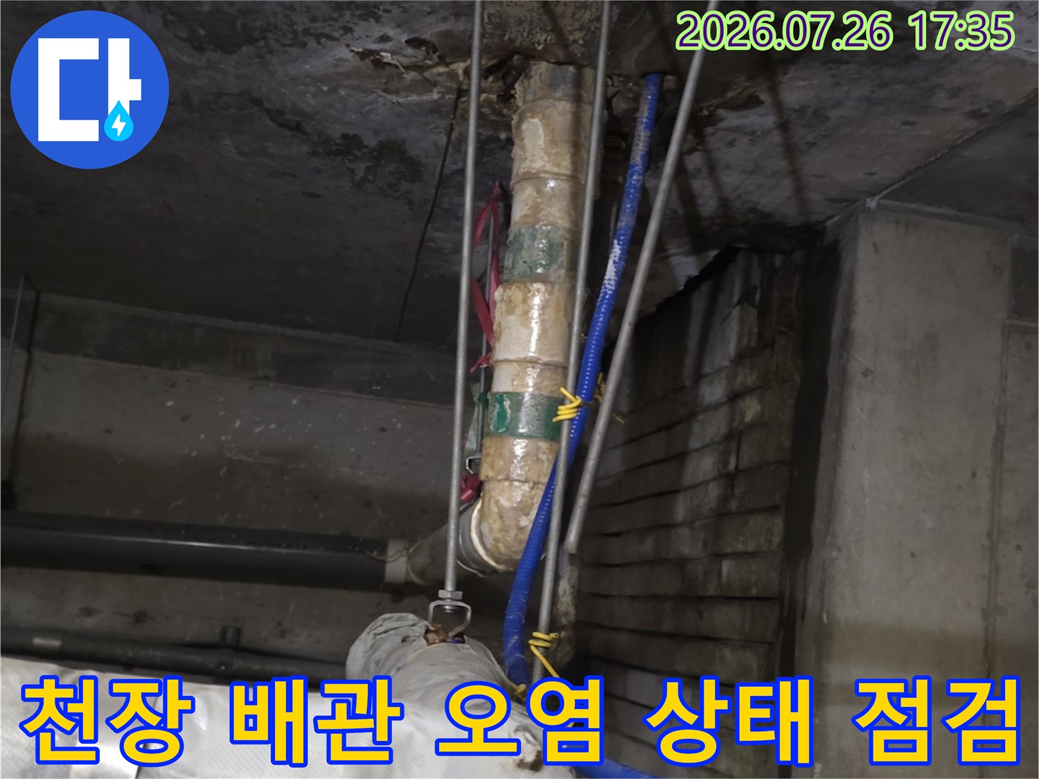 상가 천장의 콘크리트 슬래브와 누수로 인해 변색된 배관 및 파란색 호스-배선 모습