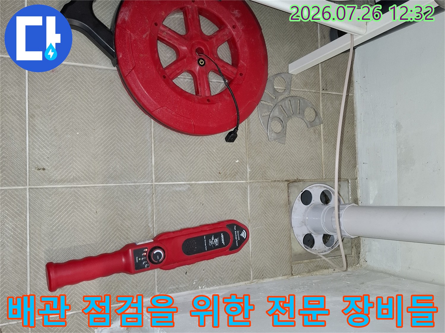 바닥 타일 위에 배치된 빨간색 누수 진단 장비와 세탁실 배관-작업 현장