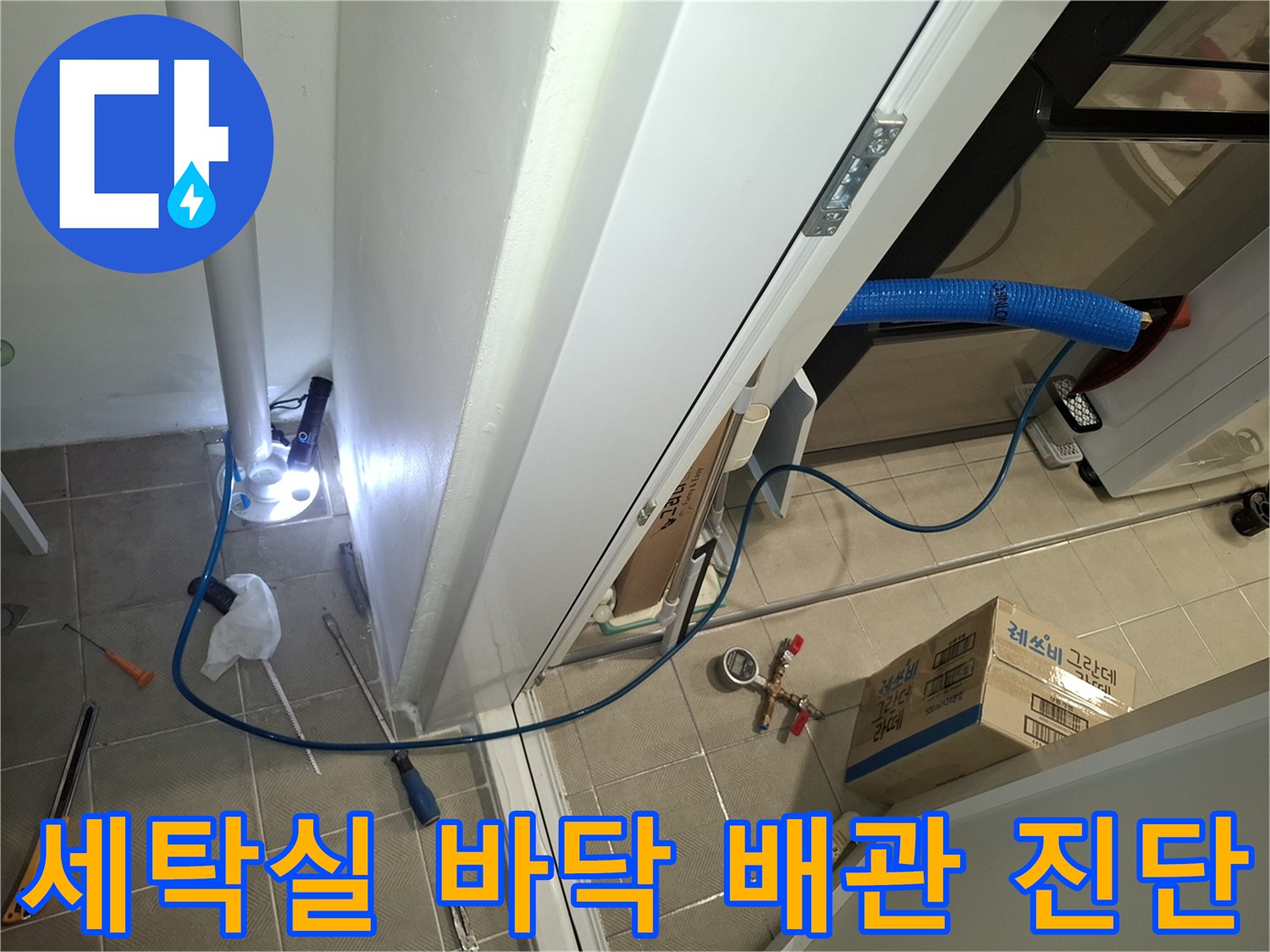 서대락실 타일 바닥에 놓인 점검용 호스와 수직 배관의 연결 부위