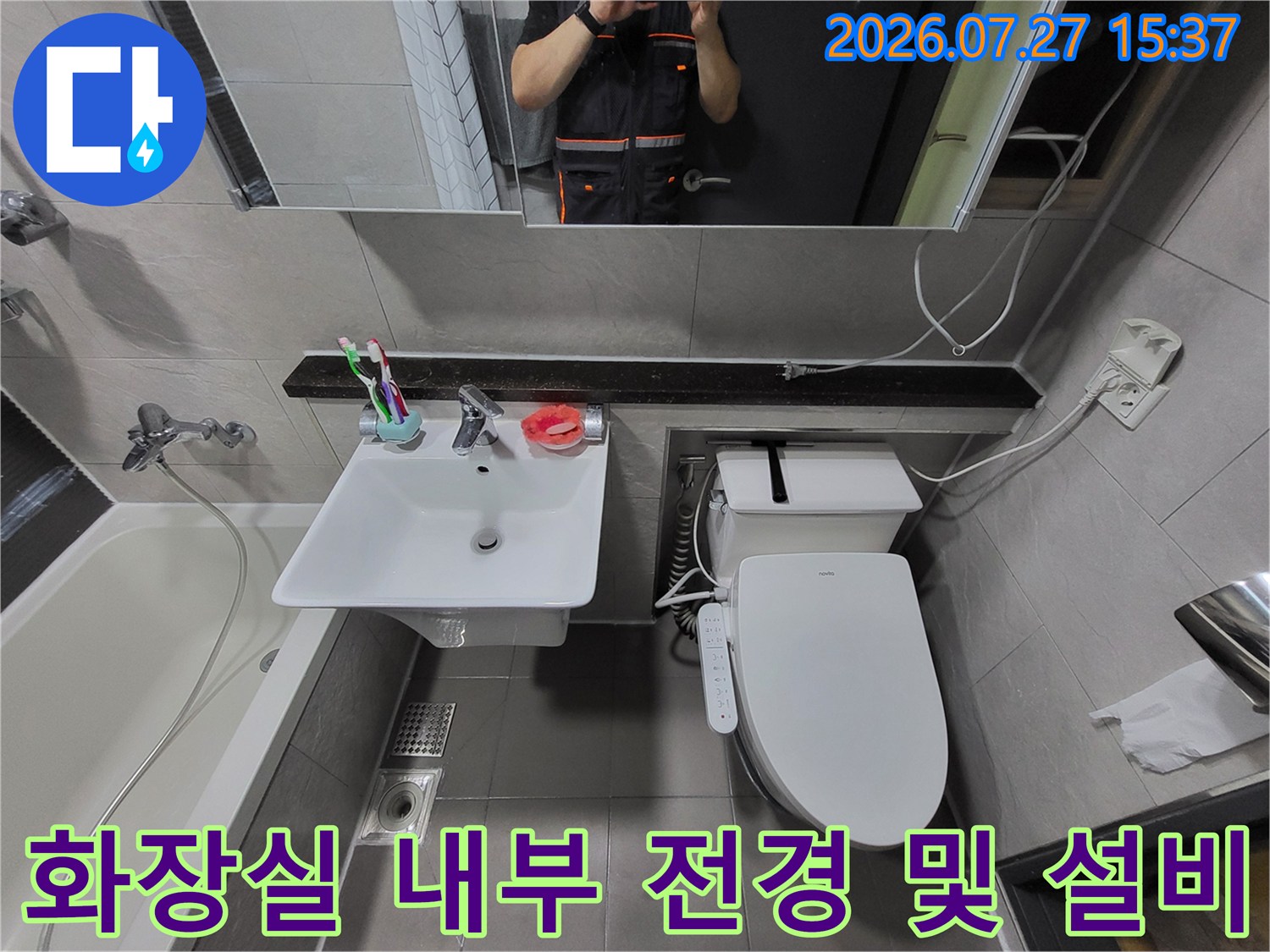 거울에 작업자가 비치는-깨끗하게 관리된 화장실의 세면대와 양변기 모습